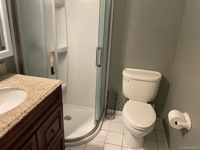 Bathroom with vanity, light tile patterned flooring, and a shower stall Bathroom with vanity, light tile patterned flooring, and a shower stall