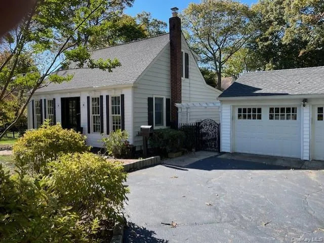 View of front facade with an outdoor structure, a chimney, a shingled roof, and a detached garage View of front facade with an outdoor structure, a chimney, a shingled roof, and a detached garage