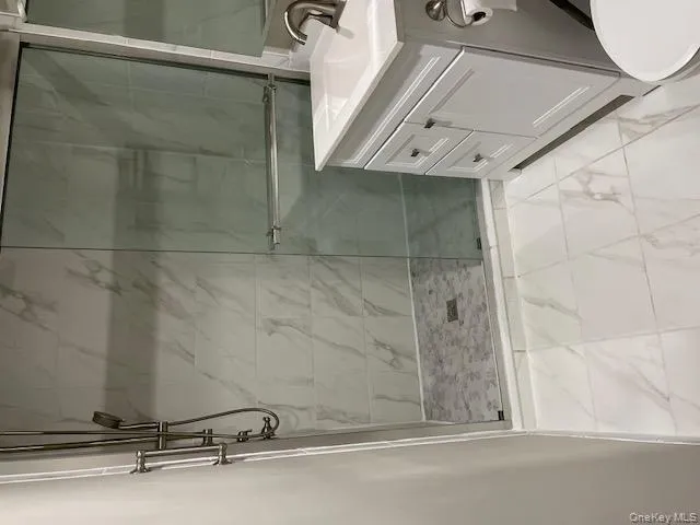 Bathroom featuring vanity, light marble finish flooring, and a marble finish shower Bathroom featuring vanity, light marble finish flooring, and a marble finish shower