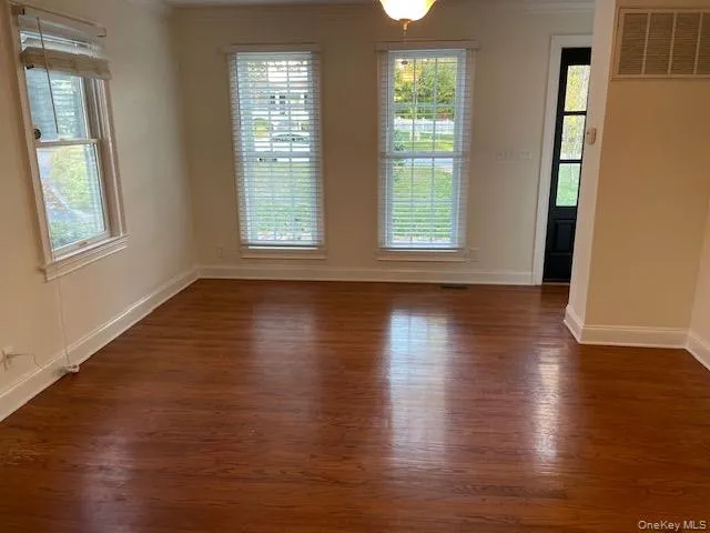 Spare room featuring crown molding and dark wood-style flooring Spare room featuring crown molding and dark wood-style flooring