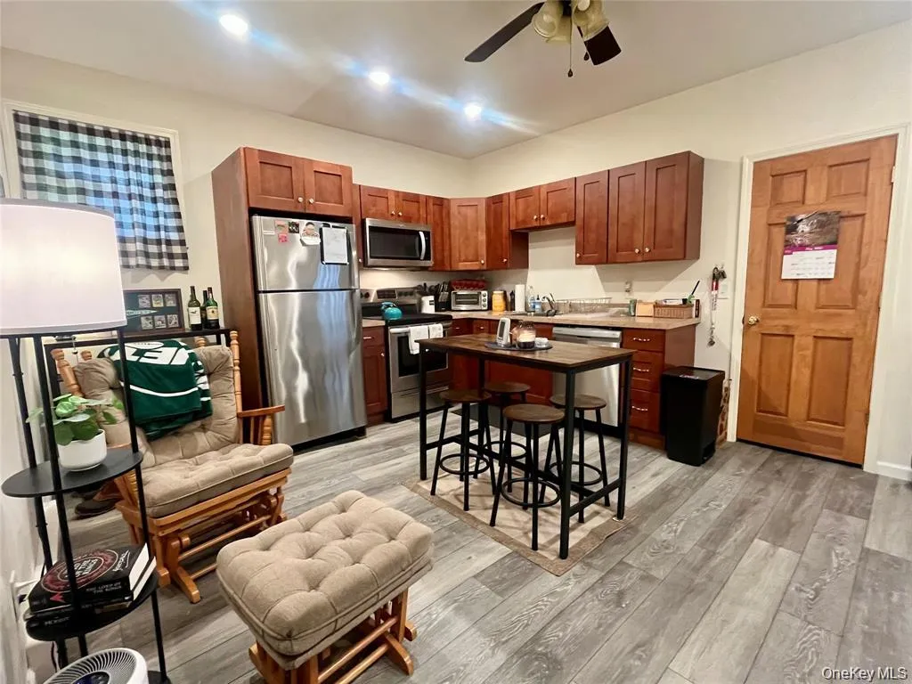 Kitchen with appliances with stainless steel finishes, light wood-type flooring, a ceiling fan, and light countertops Kitchen with appliances with stainless steel finishes, light wood-type flooring, a ceiling fan, and light countertops