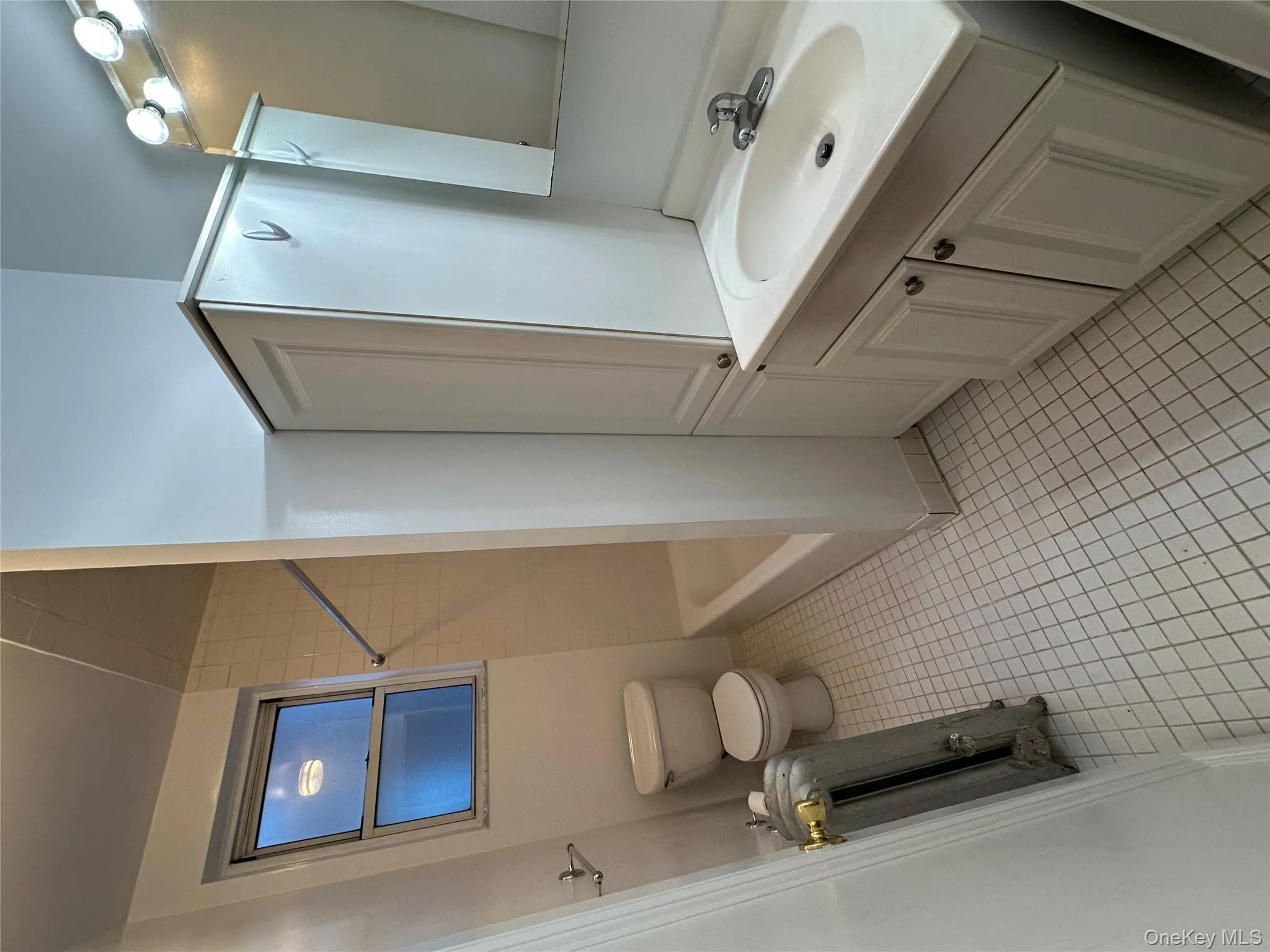 Bathroom featuring vanity, radiator, light tile patterned floors, and shower / tub combination Bathroom featuring vanity, radiator, light tile patterned floors, and shower / tub combination