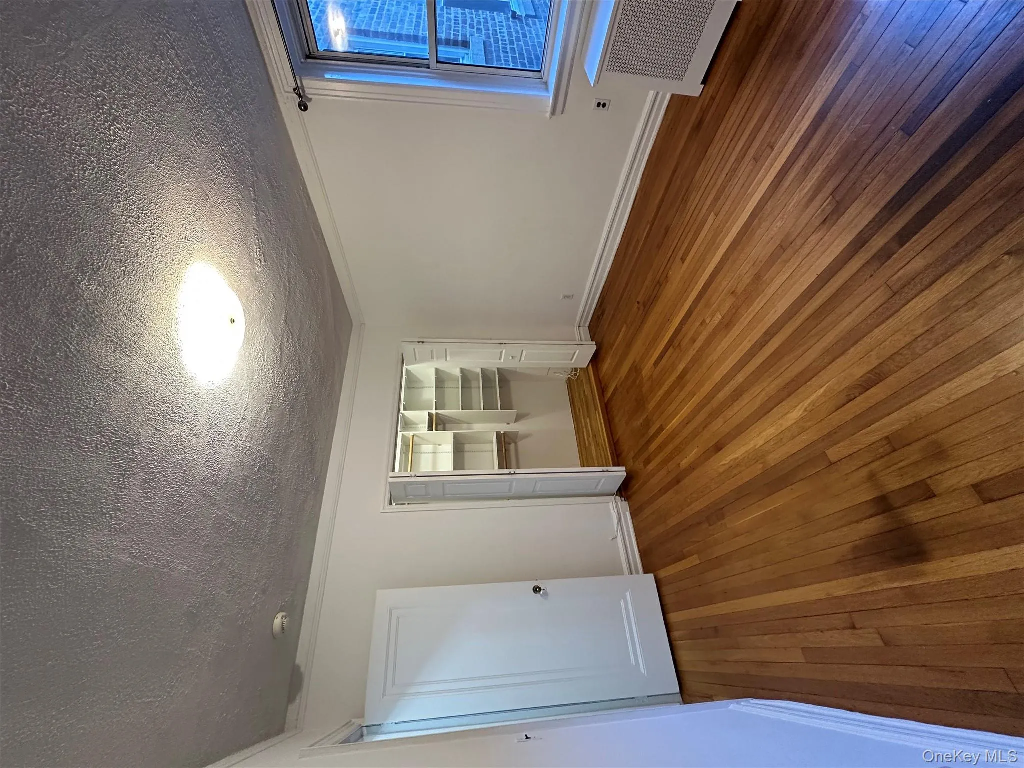 Unfurnished bedroom featuring dark wood-type flooring, radiator, a closet, and a textured ceiling Unfurnished bedroom featuring dark wood-type flooring, radiator, a closet, and a textured ceiling