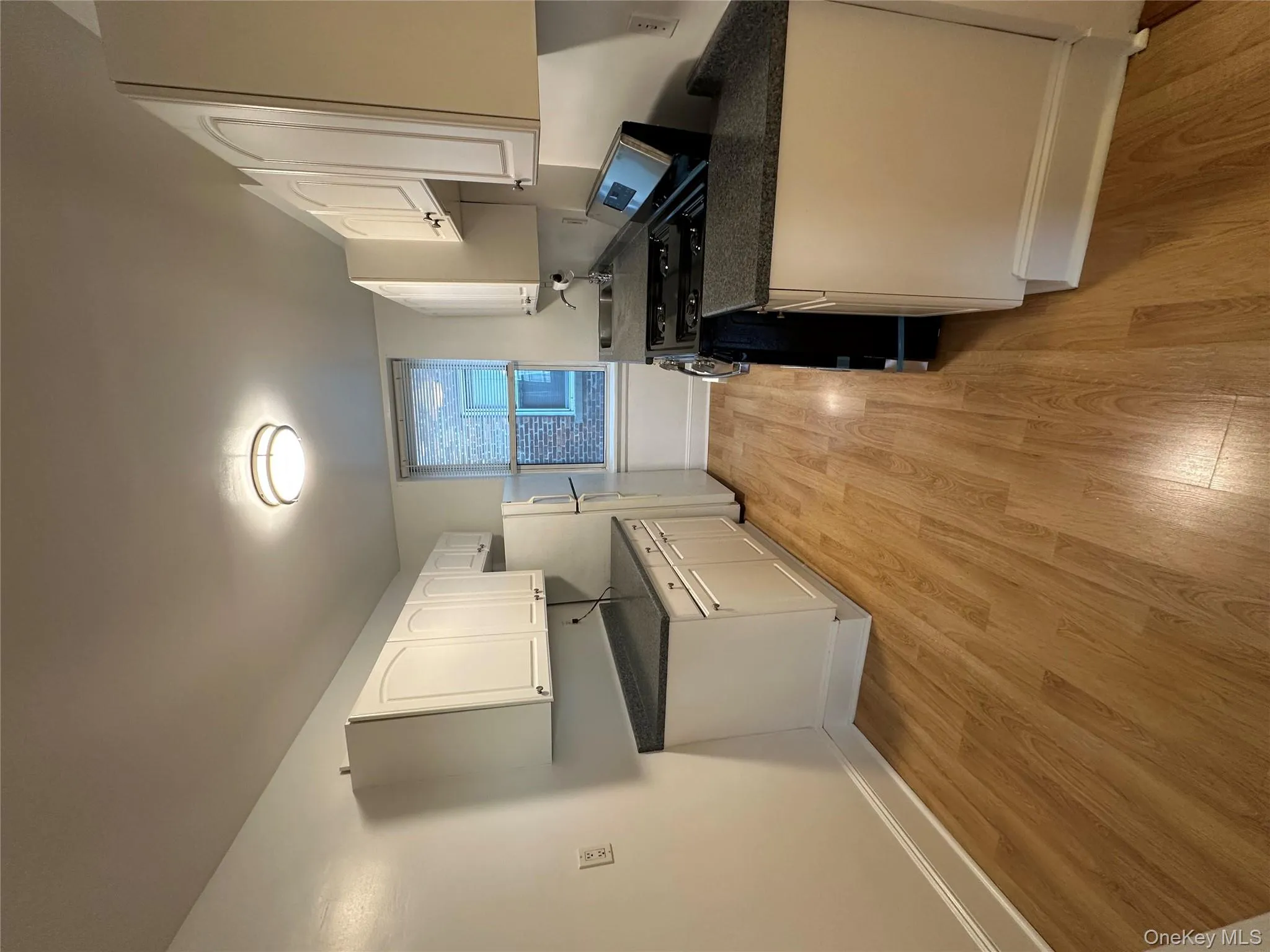 Kitchen with stove, light wood-style floors, white cabinetry, and freestanding refrigerator Kitchen with stove, light wood-style floors, white cabinetry, and freestanding refrigerator