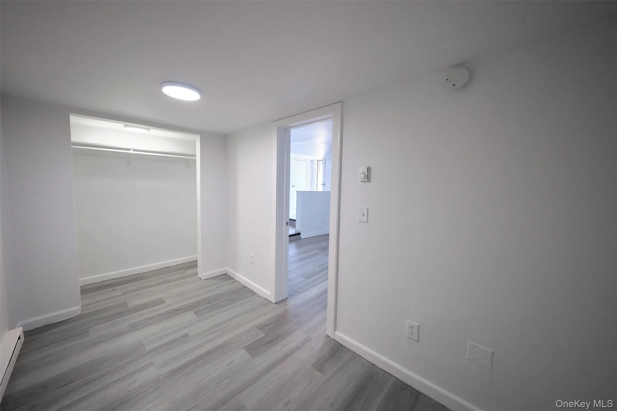 Unfurnished bedroom featuring light wood-style floors, a closet, and a baseboard heating unit Unfurnished bedroom featuring light wood-style floors, a closet, and a baseboard heating unit
