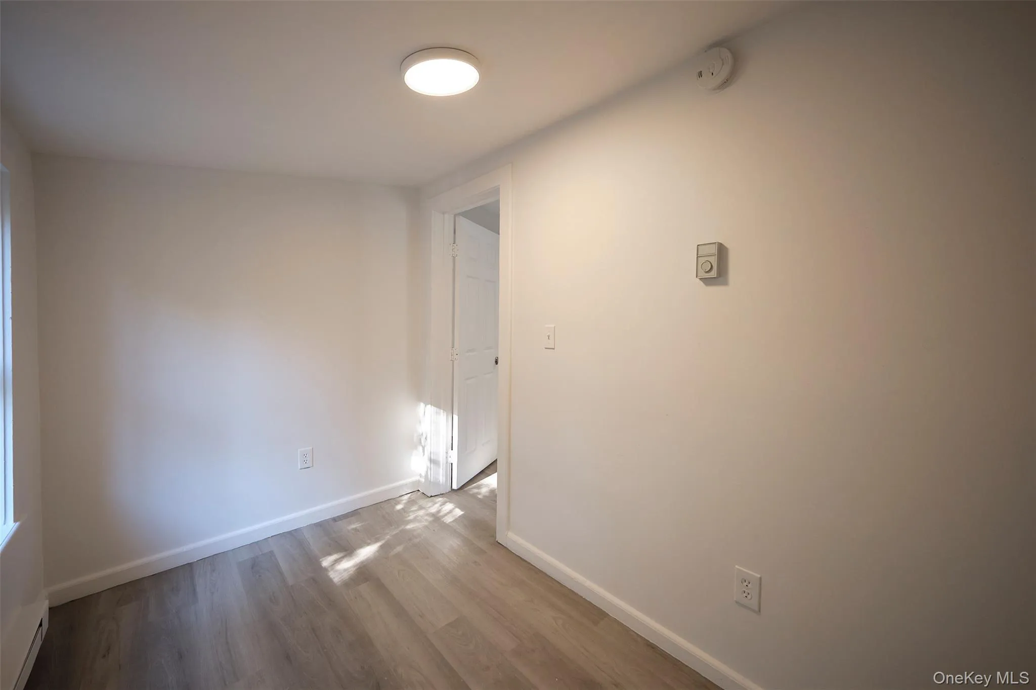 Unfurnished room with a baseboard heating unit and wood finished floors Unfurnished room with a baseboard heating unit and wood finished floors