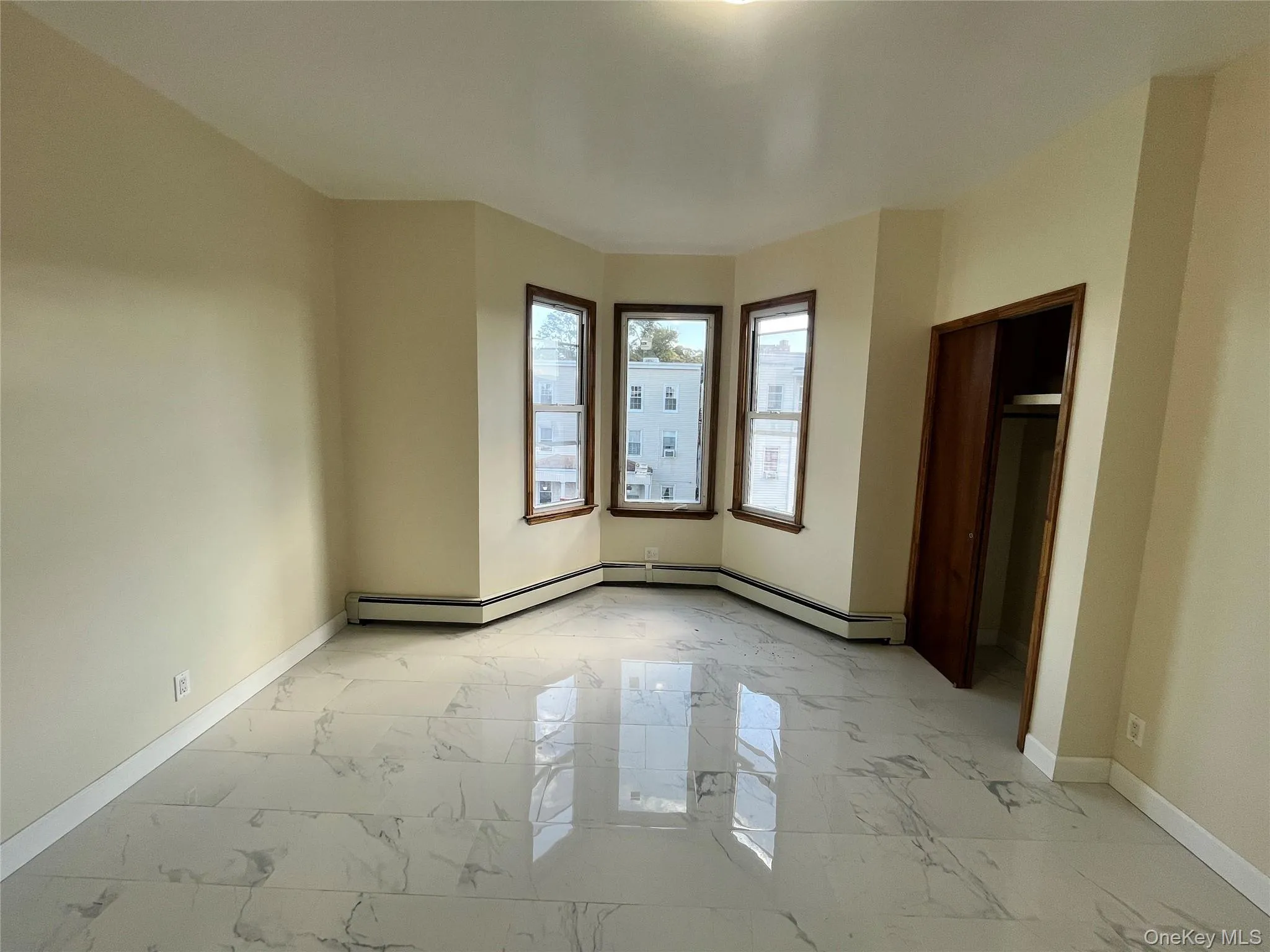 Unfurnished bedroom with light marble finish flooring and baseboard heating Unfurnished bedroom with light marble finish flooring and baseboard heating