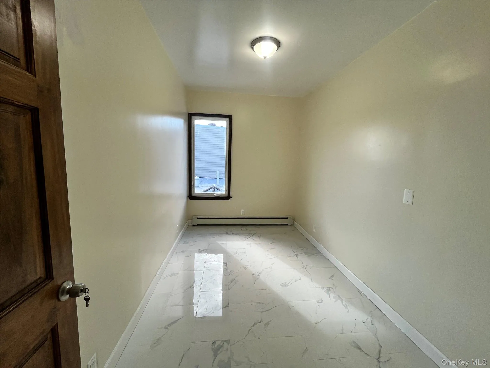 Unfurnished room with light marble finish flooring and a baseboard heating unit Unfurnished room with light marble finish flooring and a baseboard heating unit