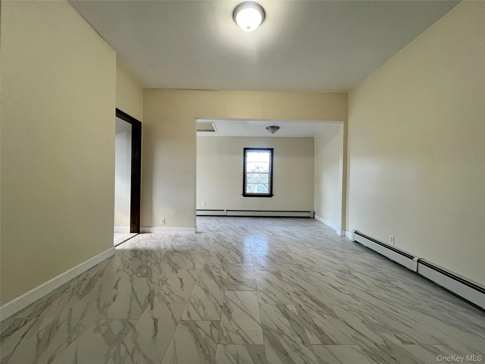 Unfurnished room featuring light marble finish floors and a baseboard radiator Unfurnished room featuring light marble finish floors and a baseboard radiator