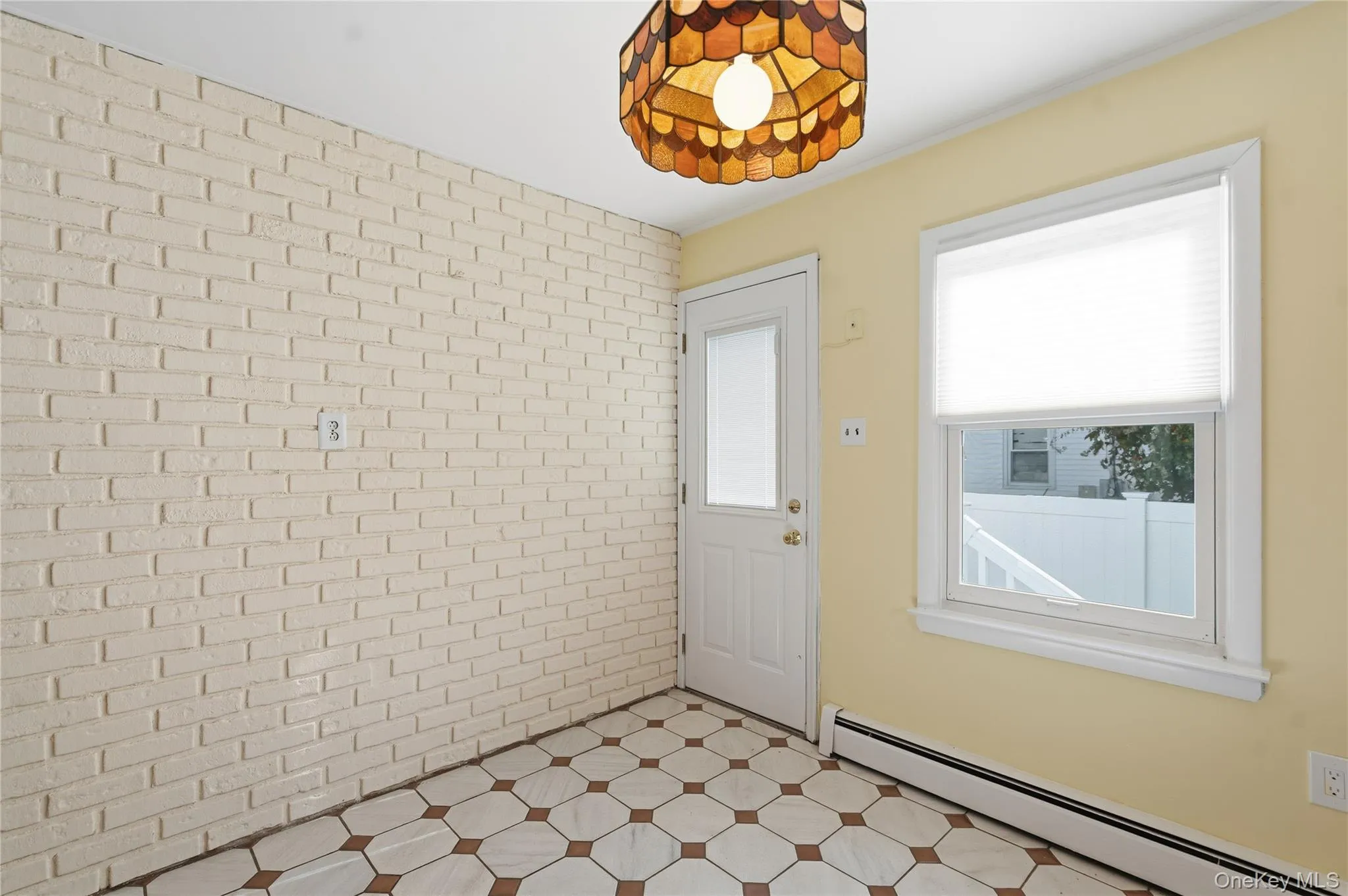Entryway with a baseboard heating unit, brick wall, and tile patterned floors Entryway with a baseboard heating unit, brick wall, and tile patterned floors