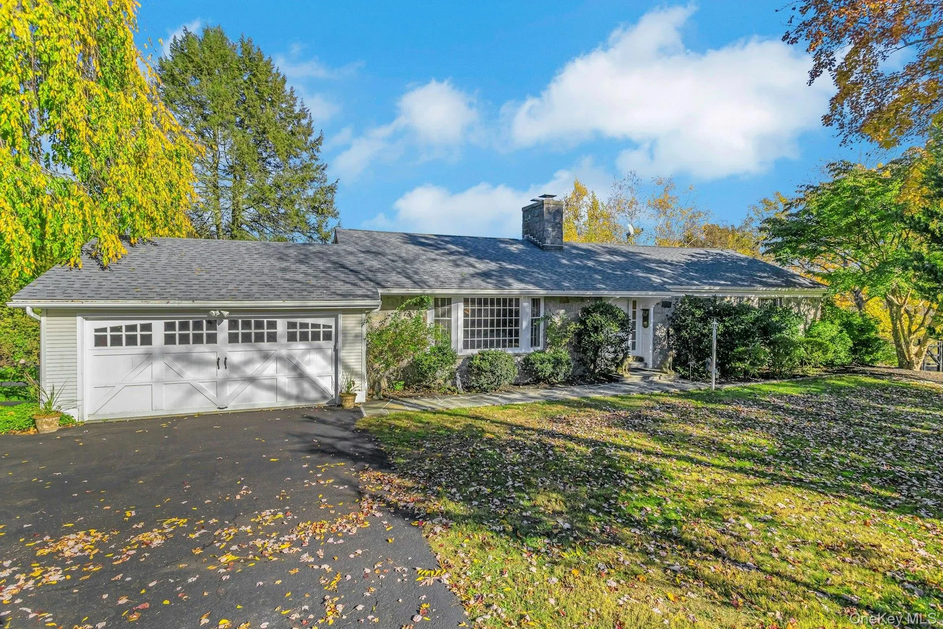 Ranch-style home featuring driveway, an attached garage, a chimney, a front yard, and roof with shingles Ranch-style home featuring driveway, an attached garage, a chimney, a front yard, and roof with shingles