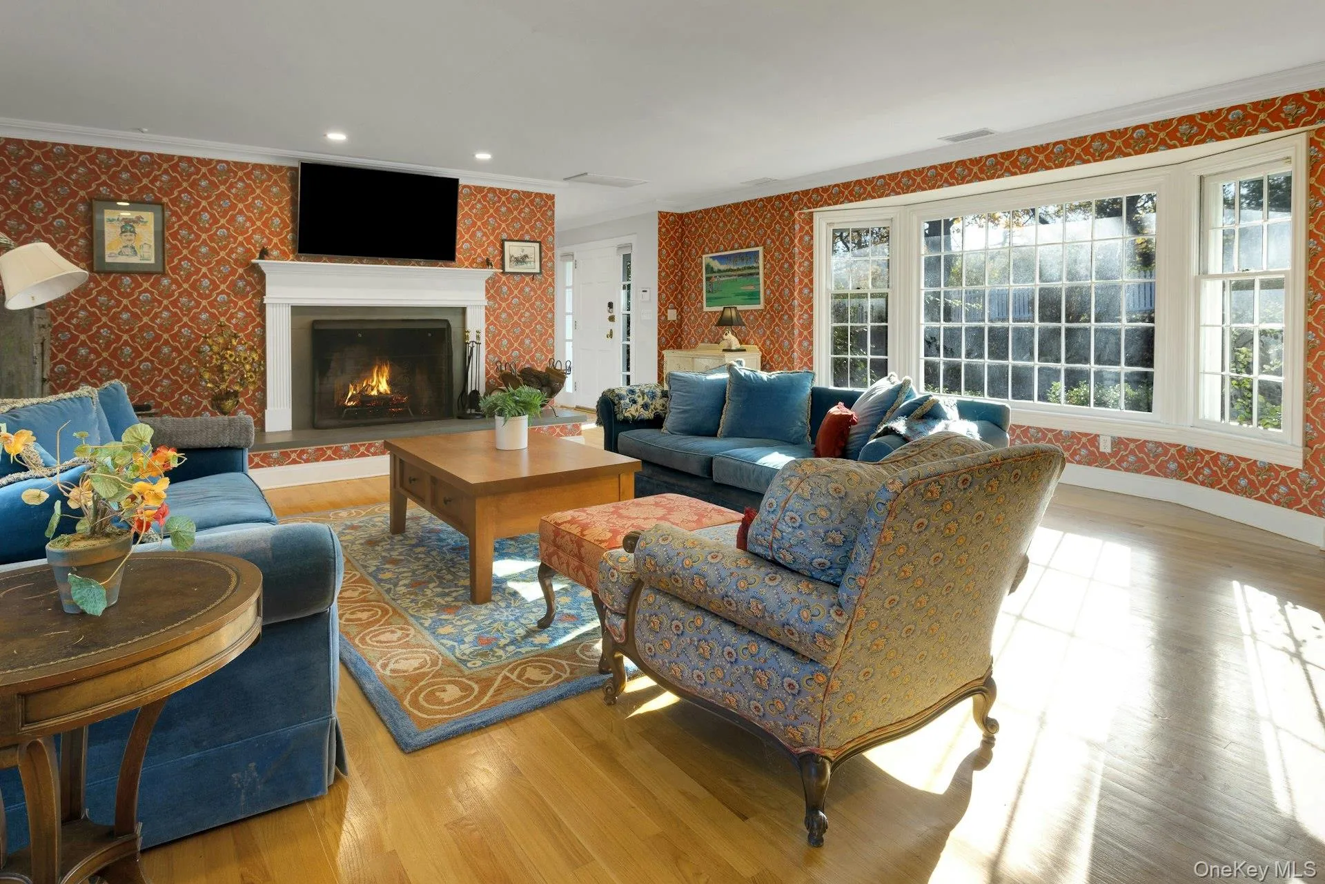 Living room featuring wallpapered walls, ornamental molding, light wood-type flooring, a lit fireplace, and recessed lighting Living room featuring wallpapered walls, ornamental molding, light wood-type flooring, a lit fireplace, and recessed lighting