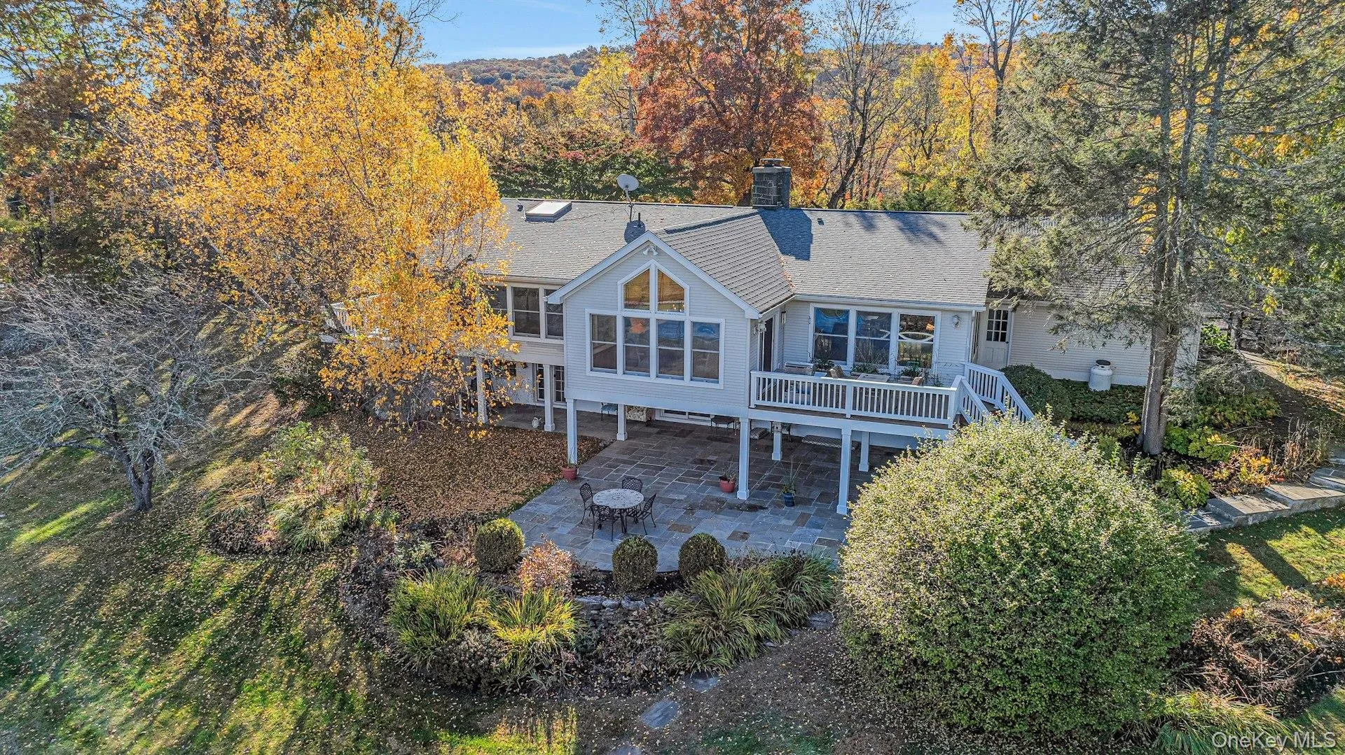 Back of house with a patio area, a chimney, a shingled roof, and a wooden deck Back of house with a patio area, a chimney, a shingled roof, and a wooden deck