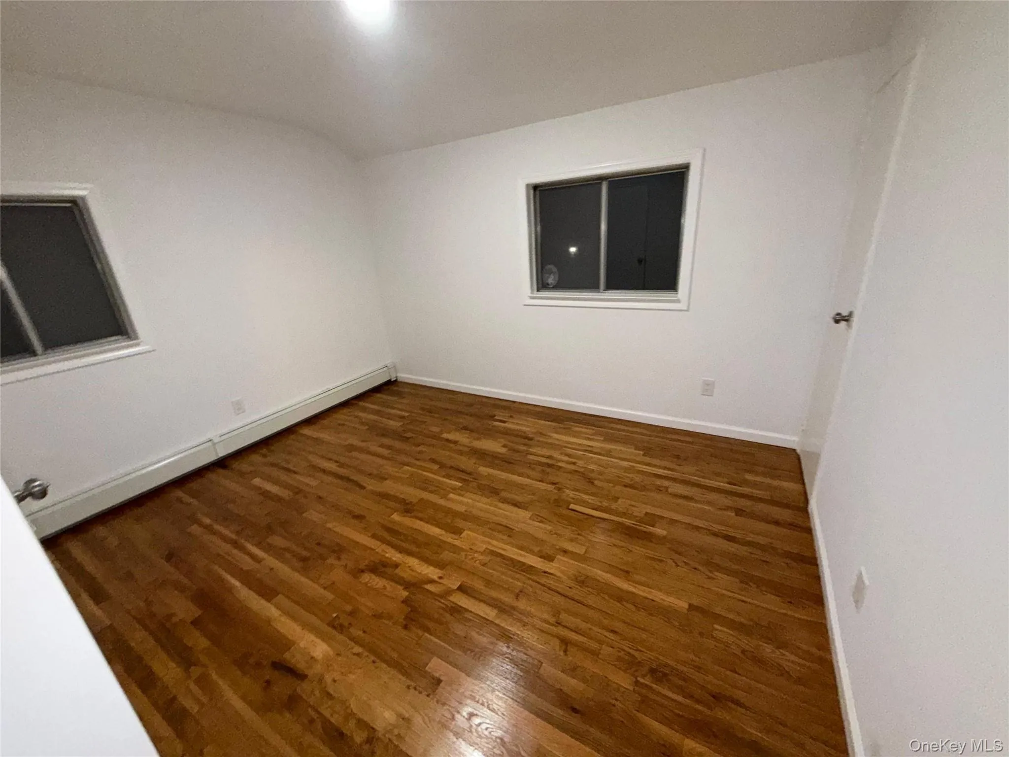 Empty room featuring a baseboard radiator and dark wood-type flooring Empty room featuring a baseboard radiator and dark wood-type flooring
