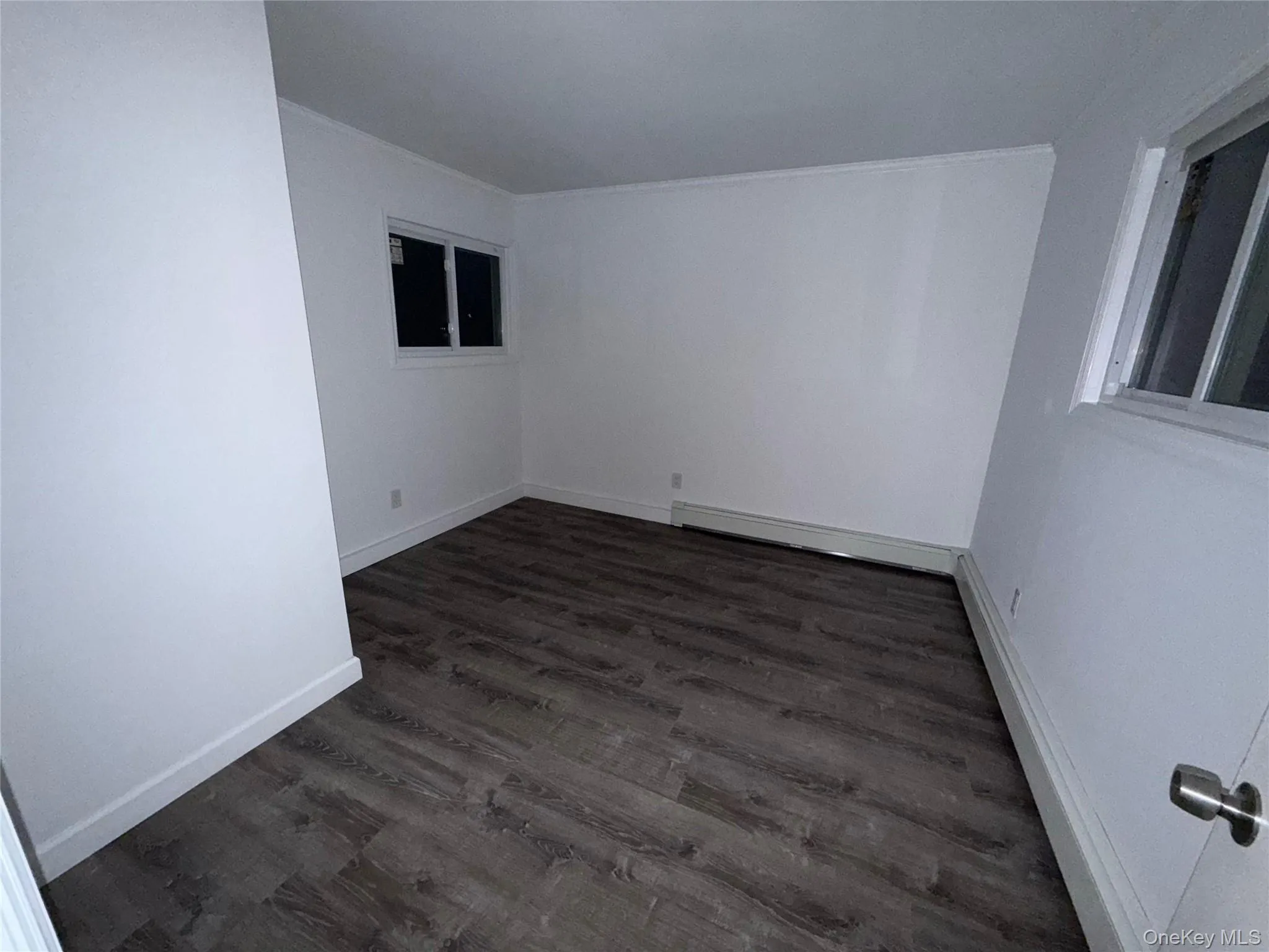 Unfurnished room with dark wood-type flooring and a baseboard radiator Unfurnished room with dark wood-type flooring and a baseboard radiator