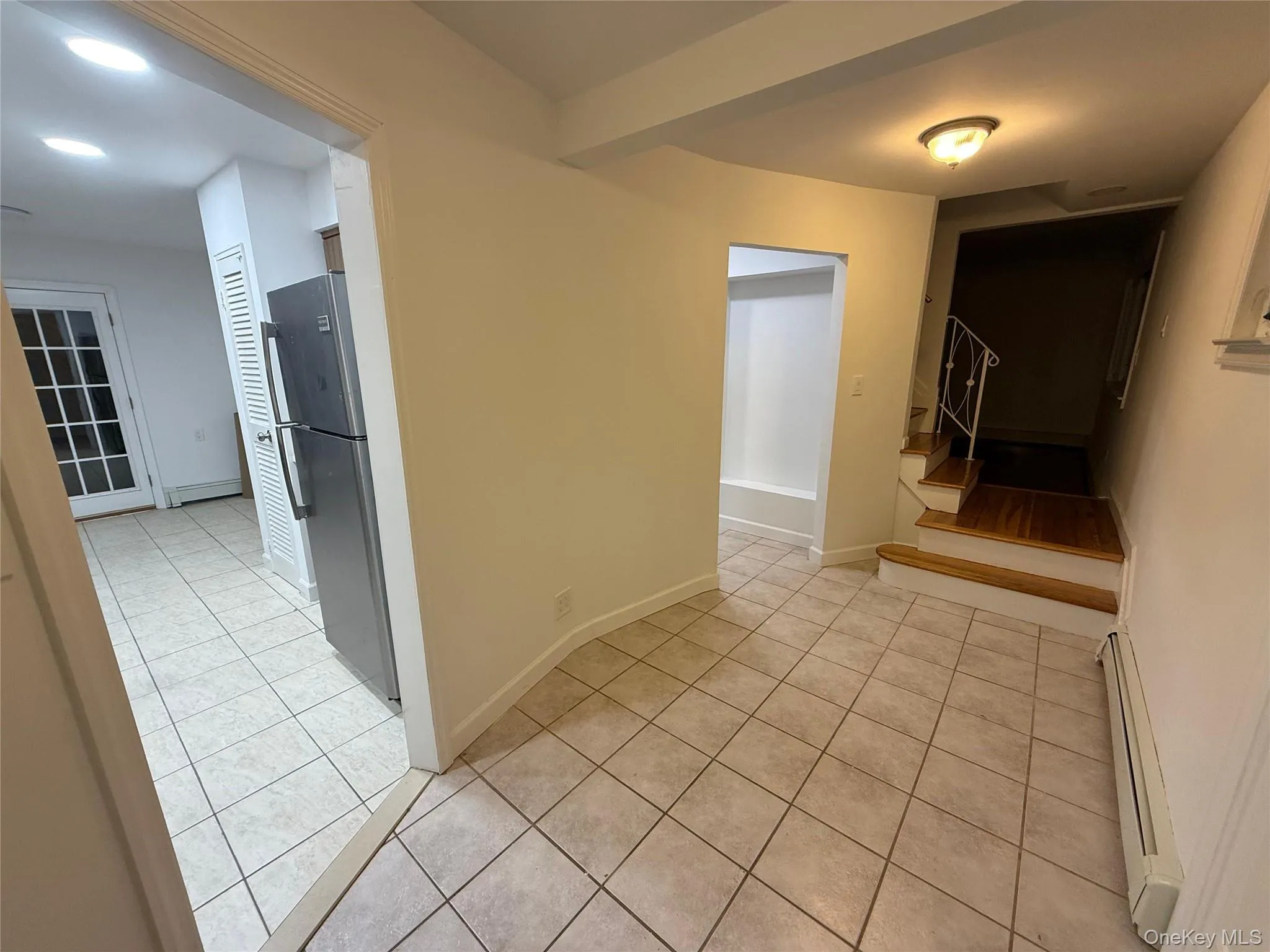 Hall with light tile patterned flooring, a baseboard heating unit, and stairway Hall with light tile patterned flooring, a baseboard heating unit, and stairway