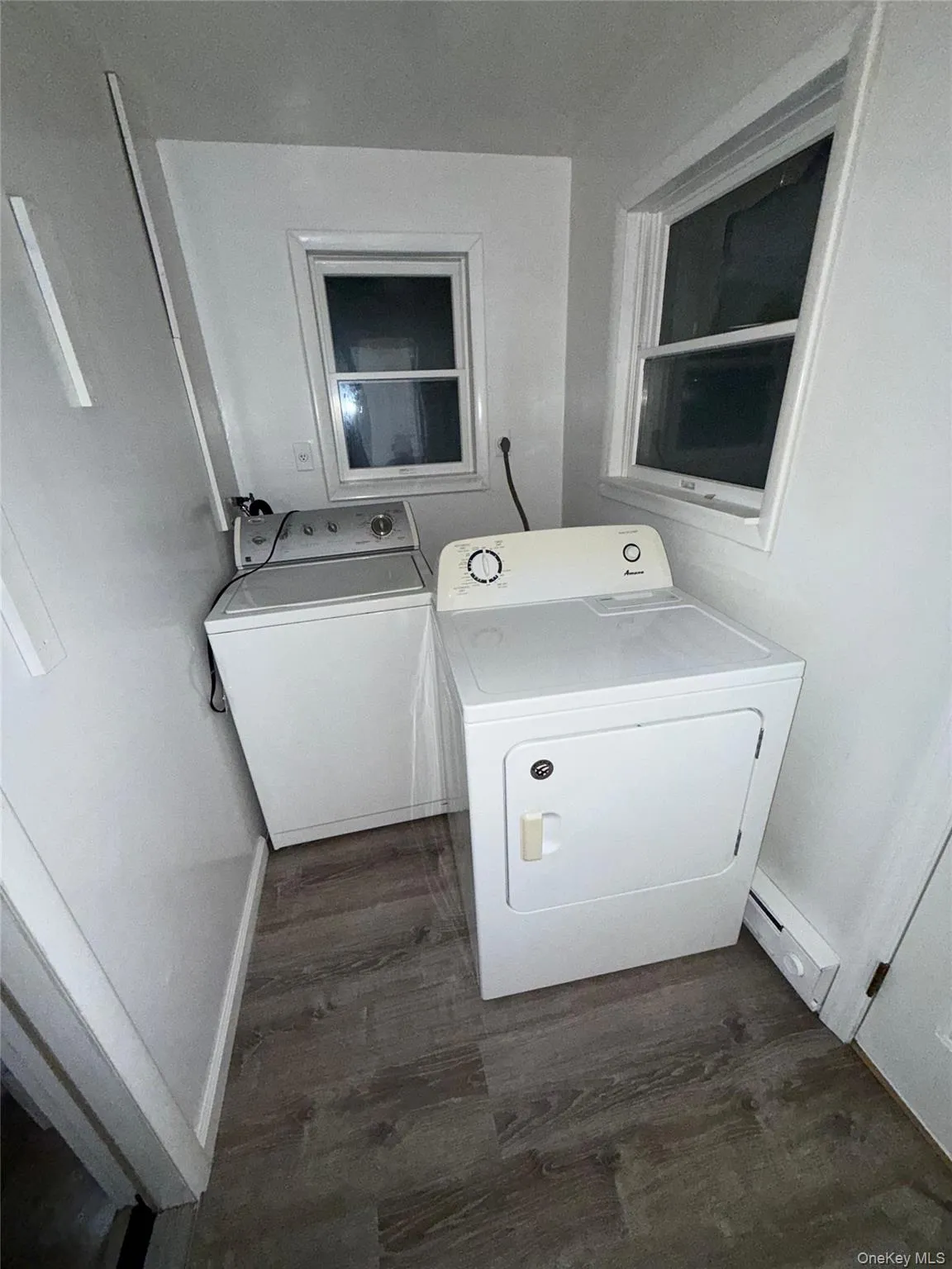 Washroom with washing machine and clothes dryer and dark wood-style floors Washroom with washing machine and clothes dryer and dark wood-style floors
