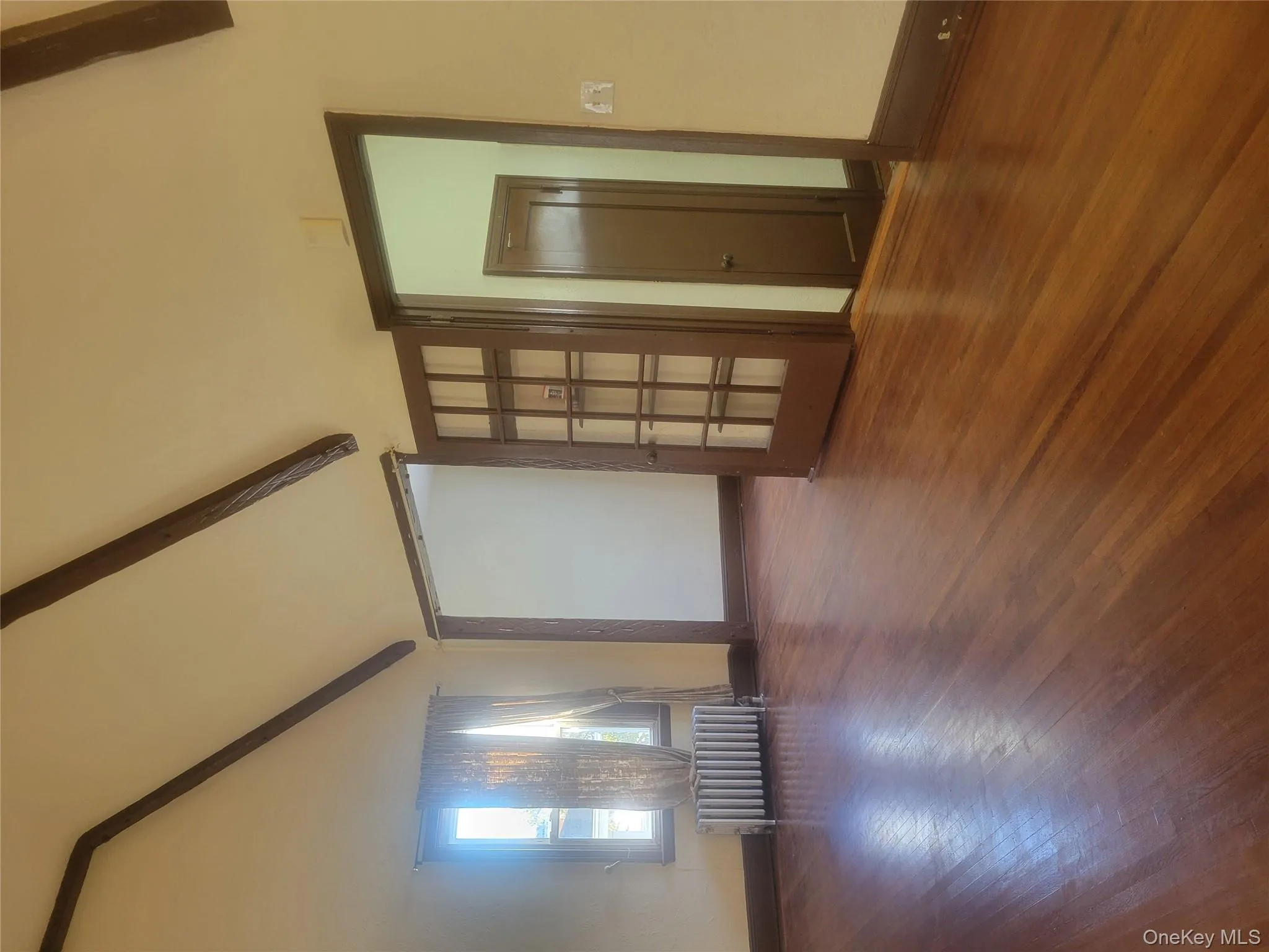 Empty room with beam ceiling, wood finished floors, radiator heating unit, and high vaulted ceiling Empty room with beam ceiling, wood finished floors, radiator heating unit, and high vaulted ceiling