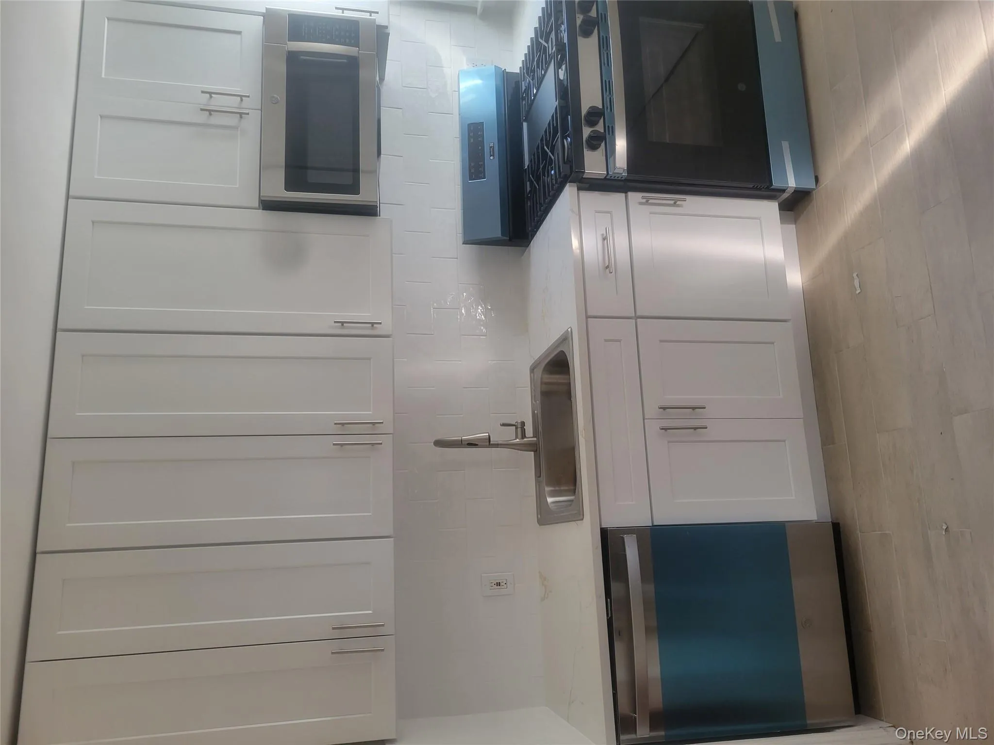 Kitchen featuring stainless steel range, dishwashing machine, backsplash, white cabinetry, and light stone counters Kitchen featuring stainless steel range, dishwashing machine, backsplash, white cabinetry, and light stone counters