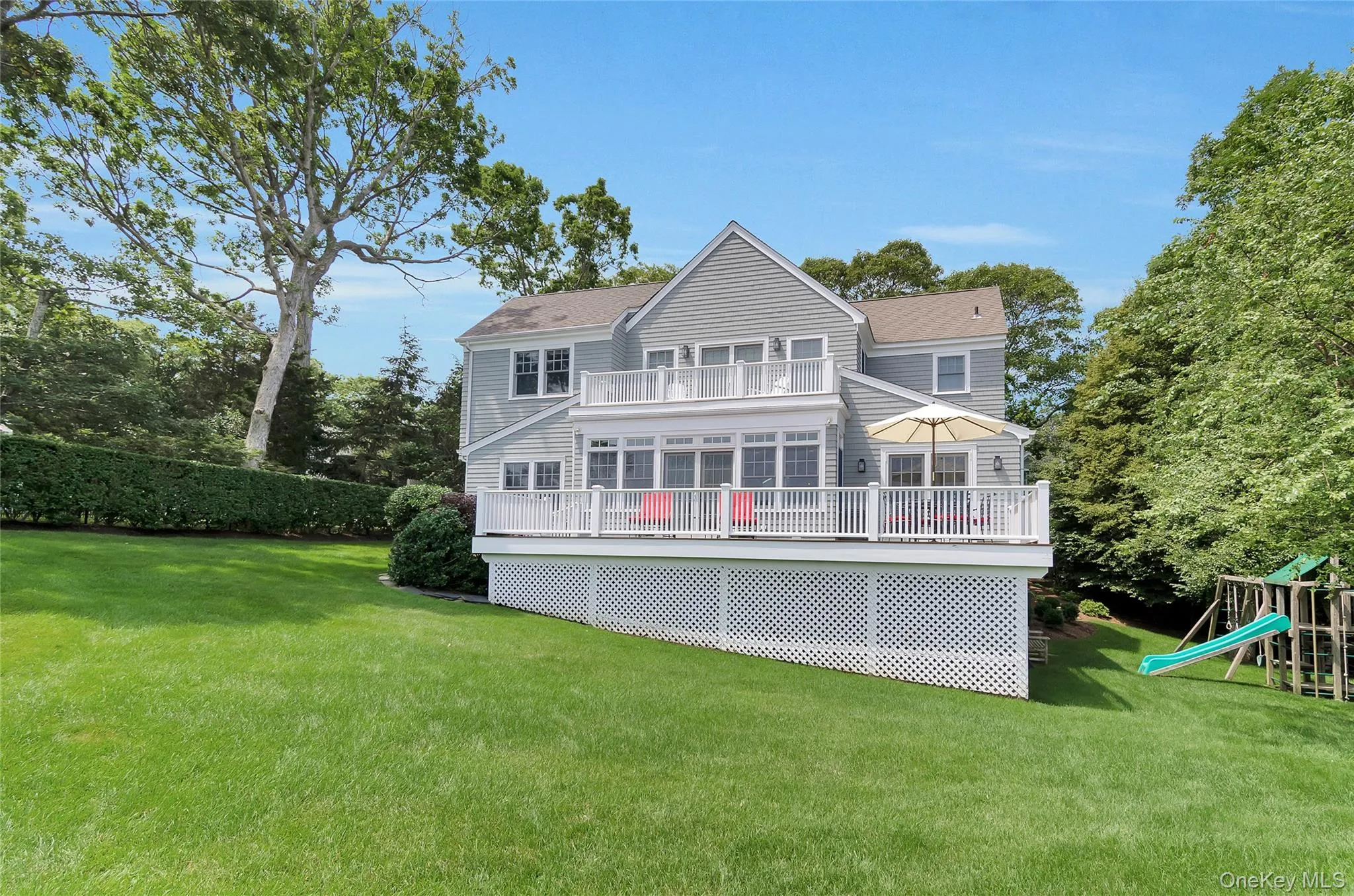 Back of house featuring a playground, a yard, and a deck Back of house featuring a playground, a yard, and a deck