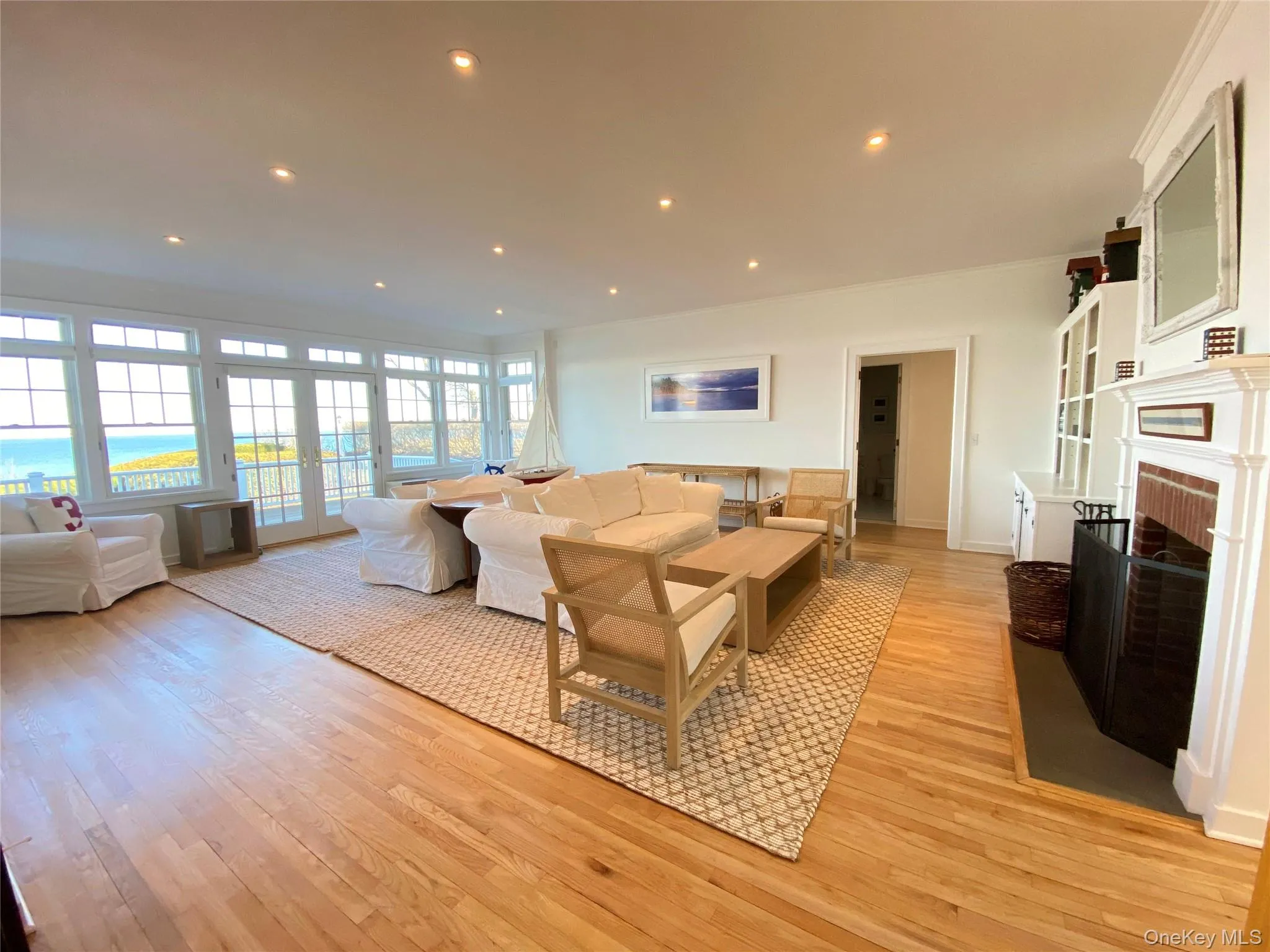 Living area featuring recessed lighting, light wood-style floors, a brick fireplace, crown molding, and french doors Living area featuring recessed lighting, light wood-style floors, a brick fireplace, crown molding, and french doors