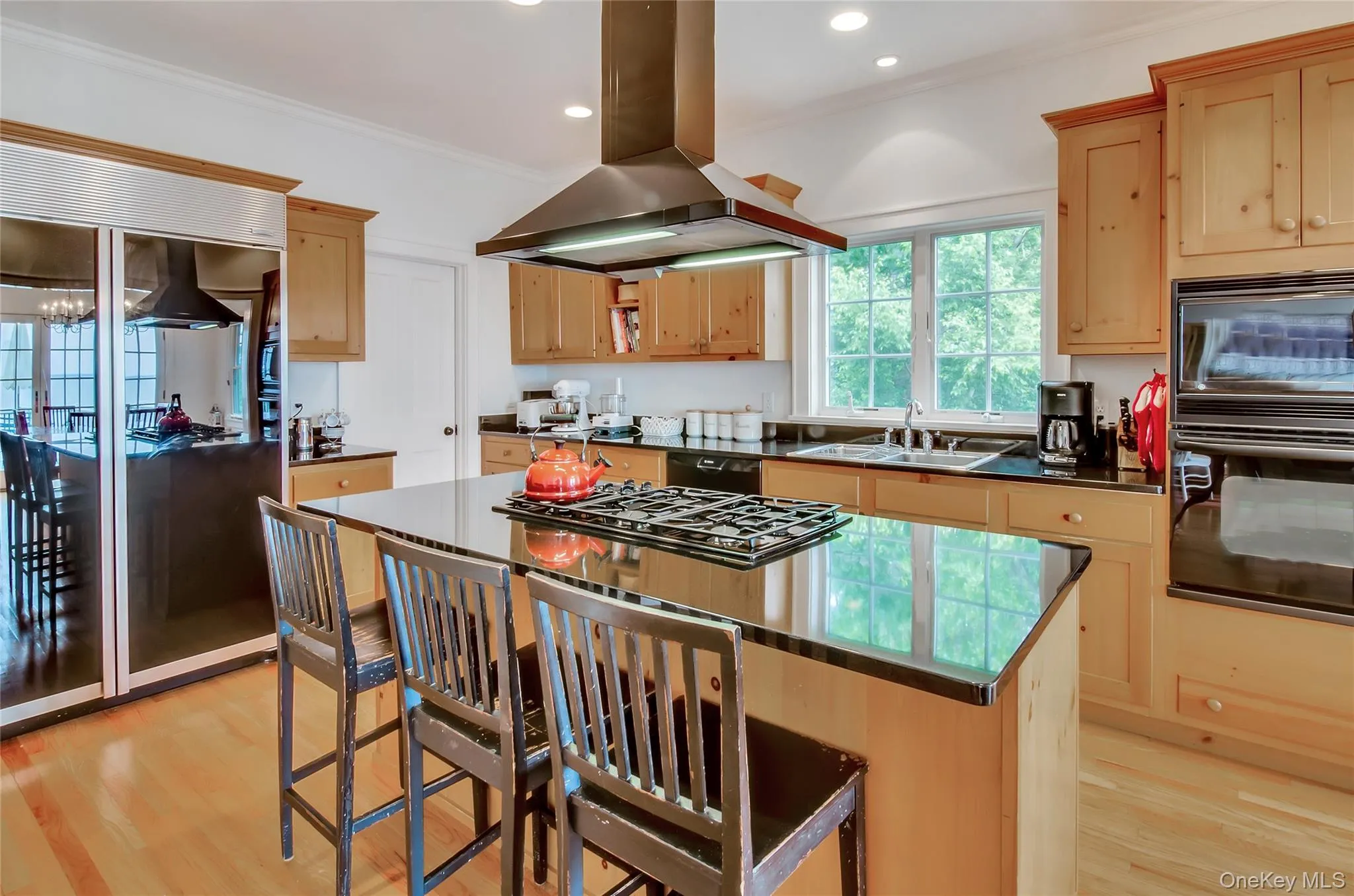 Kitchen featuring island exhaust hood, a kitchen island, light brown cabinets, black appliances, and crown molding Kitchen featuring island exhaust hood, a kitchen island, light brown cabinets, black appliances, and crown molding