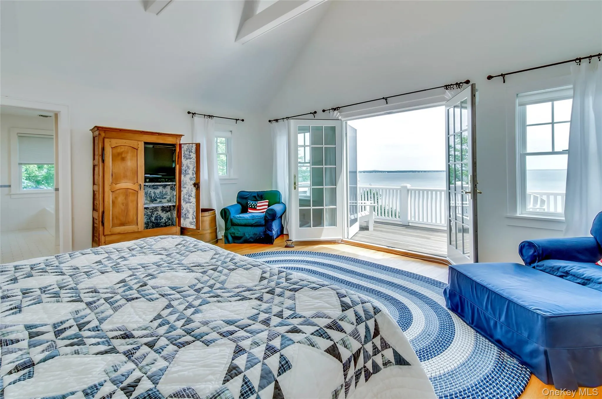 Primary bedroom with high vaulted ceiling, wood finished floors, and access to outside Primary bedroom with high vaulted ceiling, wood finished floors, and access to outside