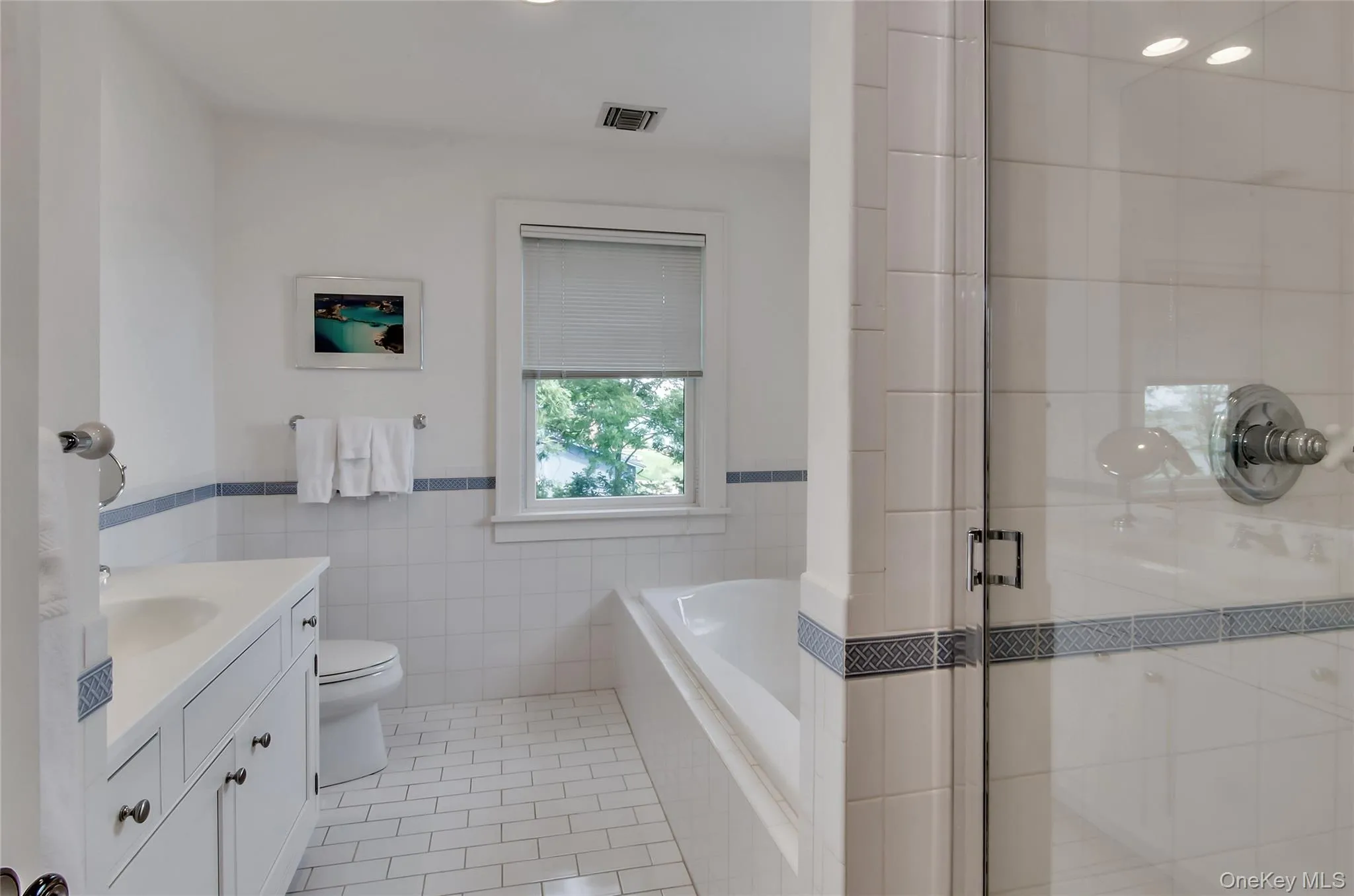 Primary bathroom with vanity, tile walls, light tile patterned floors, a shower stall, and a bath Primary bathroom with vanity, tile walls, light tile patterned floors, a shower stall, and a bath