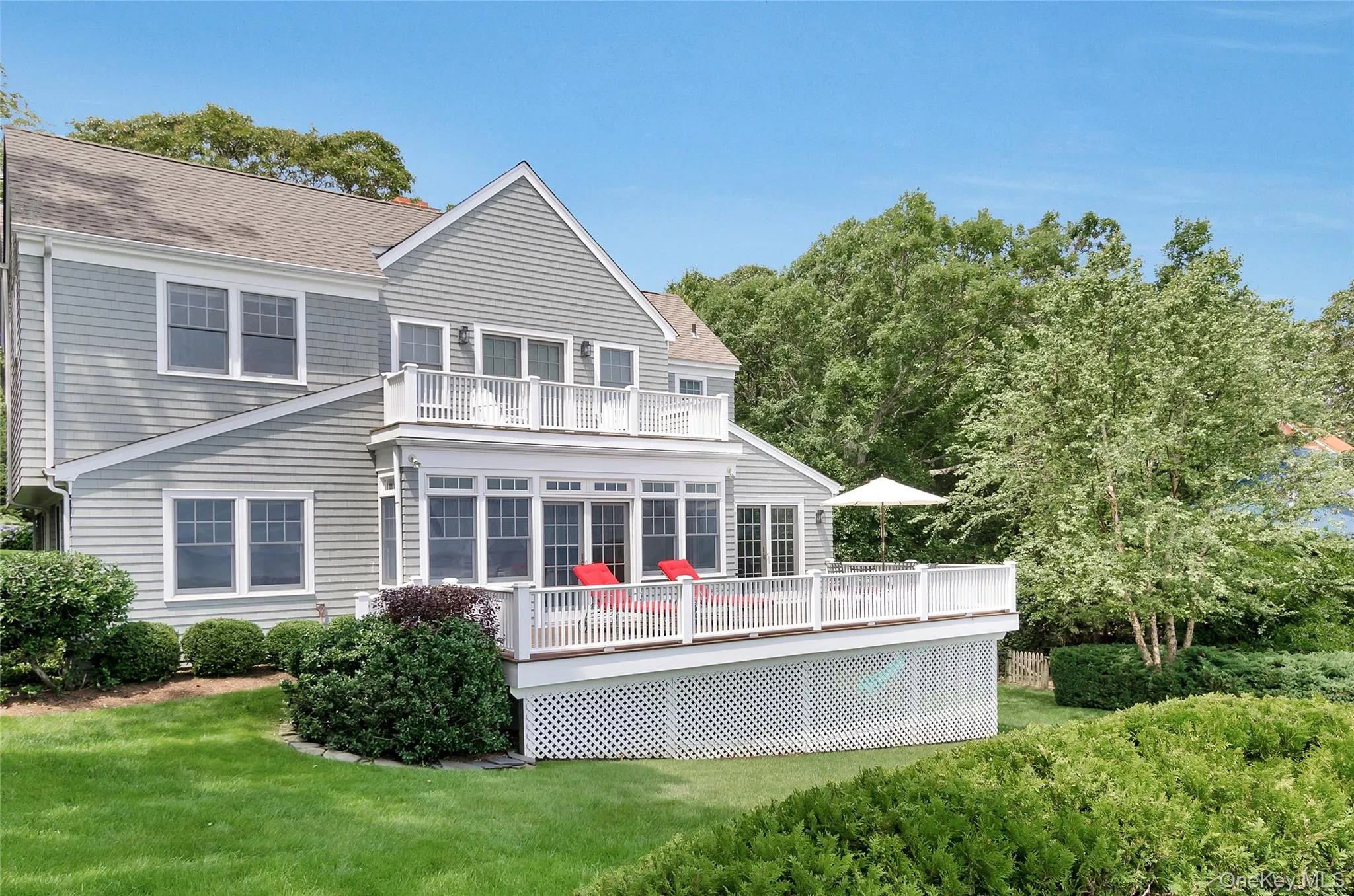 Rear view of property with a wooden deck, a shingled roof, and a lawn Rear view of property with a wooden deck, a shingled roof, and a lawn