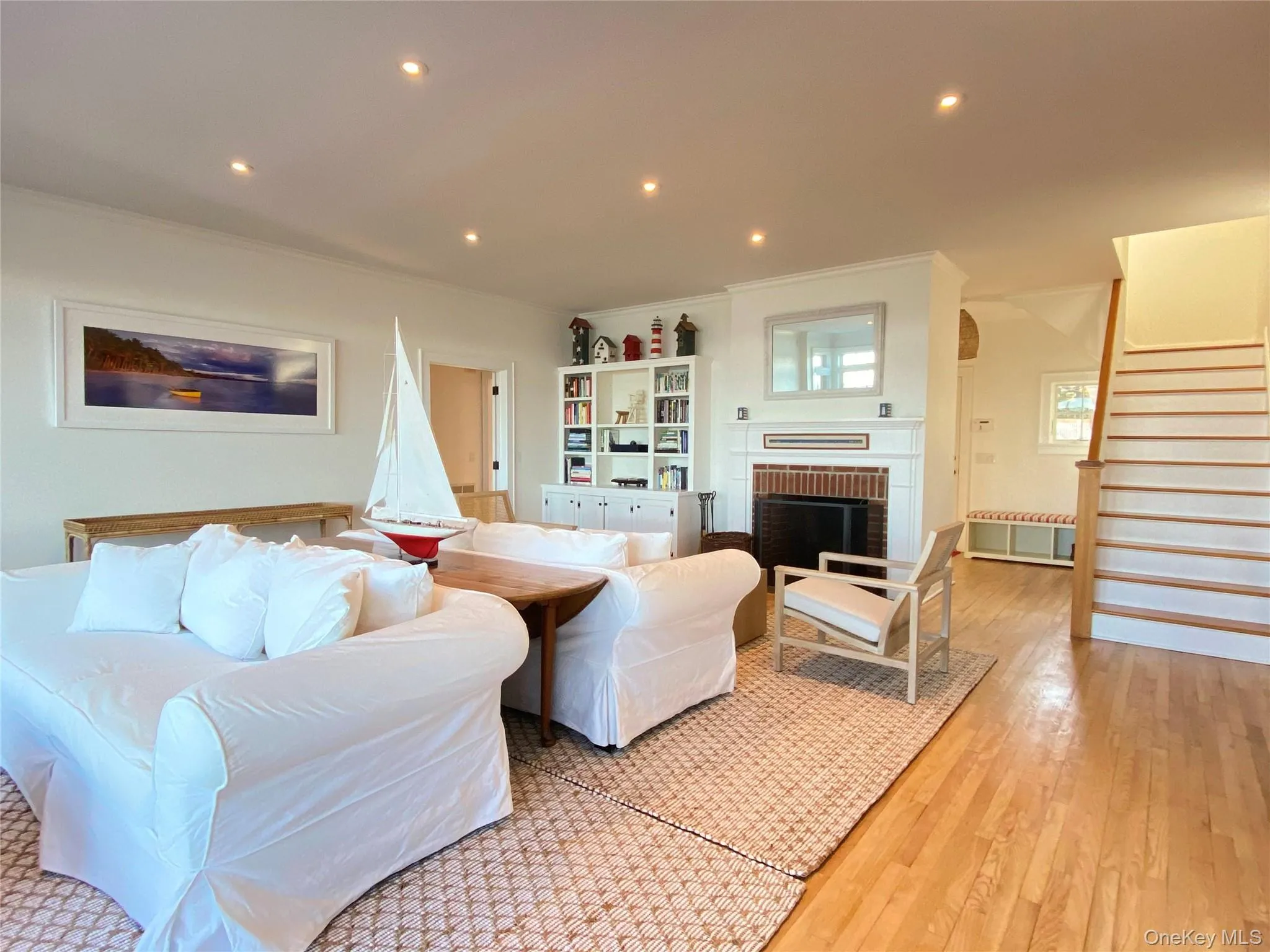 Living room with a fireplace, crown molding, recessed lighting, hardwood / wood-style flooring, and stairs Living room with a fireplace, crown molding, recessed lighting, hardwood / wood-style flooring, and stairs