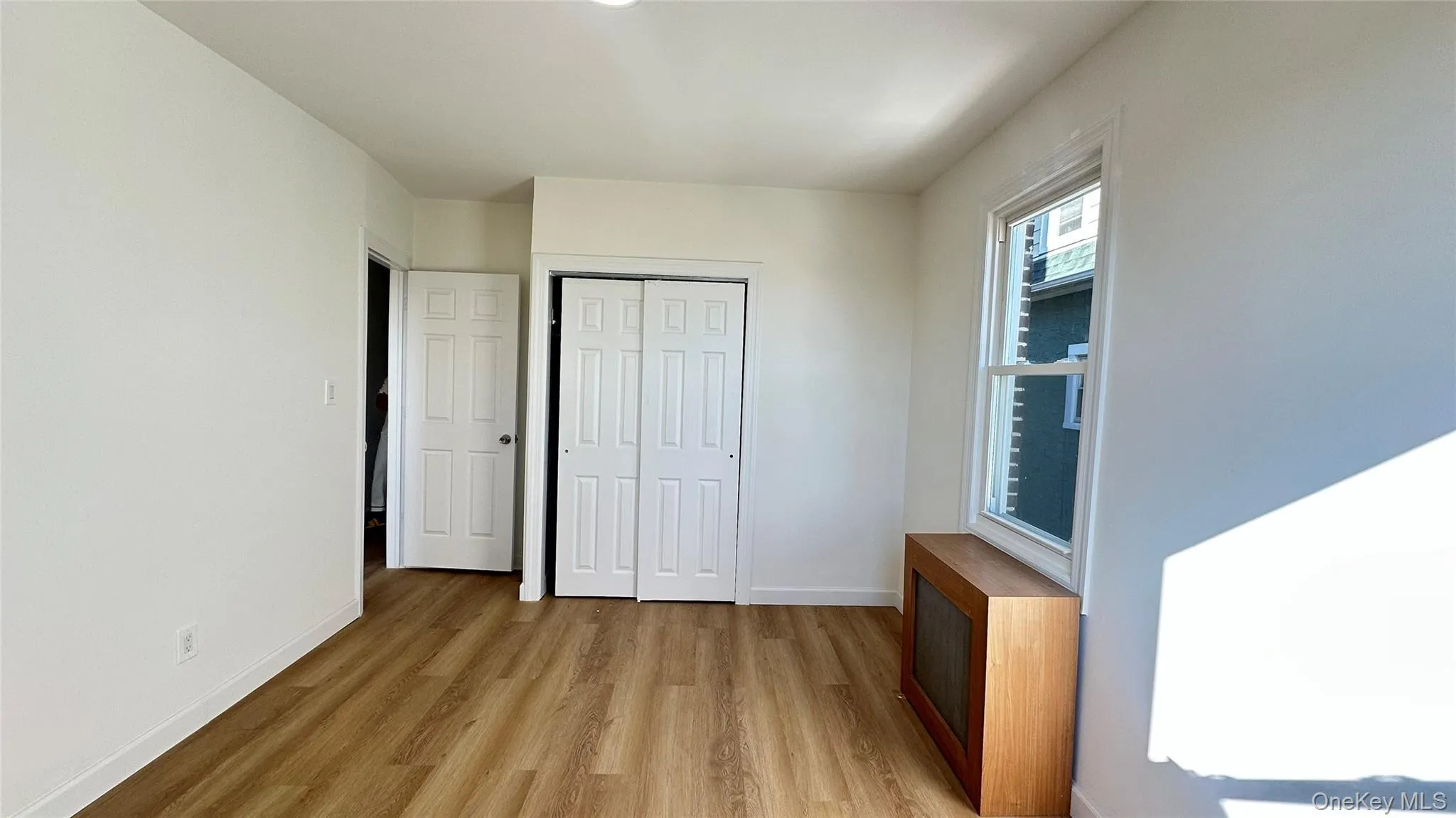 Unfurnished bedroom featuring light wood-type flooring, a closet, and radiator heating unit Unfurnished bedroom featuring light wood-type flooring, a closet, and radiator heating unit