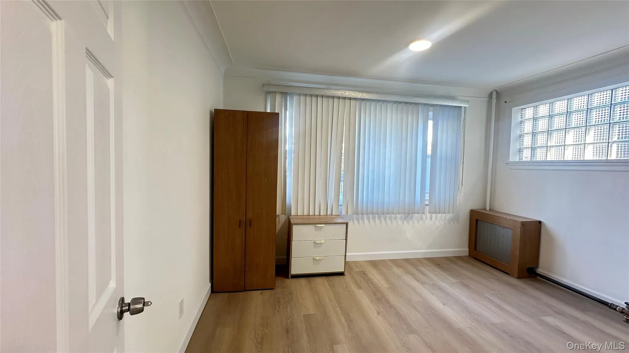 Unfurnished bedroom featuring light wood-style flooring, radiator, and ornamental molding Unfurnished bedroom featuring light wood-style flooring, radiator, and ornamental molding