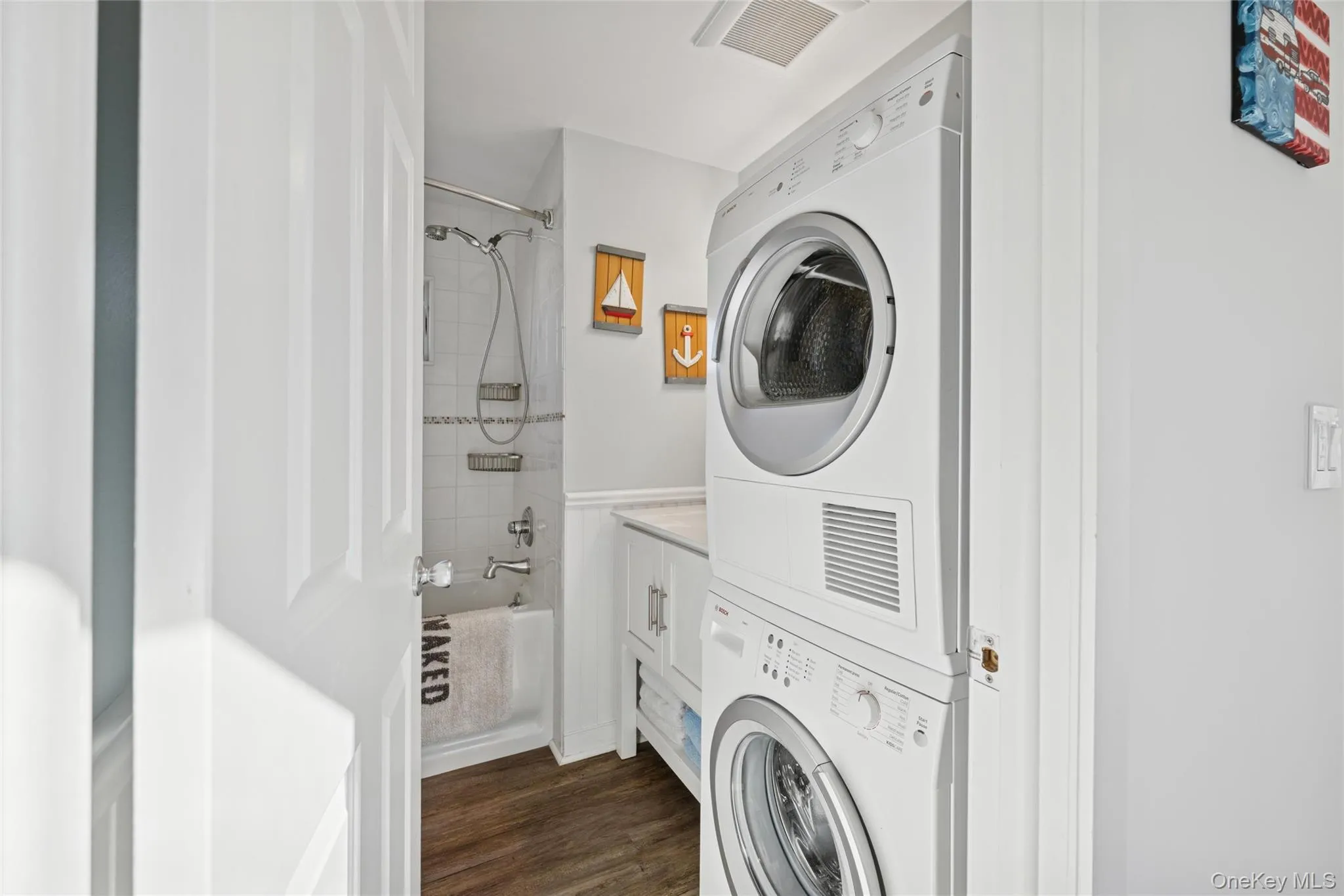 Washroom featuring dark wood finished floors and estacked washer and dryer Washroom featuring dark wood finished floors and estacked washer and dryer