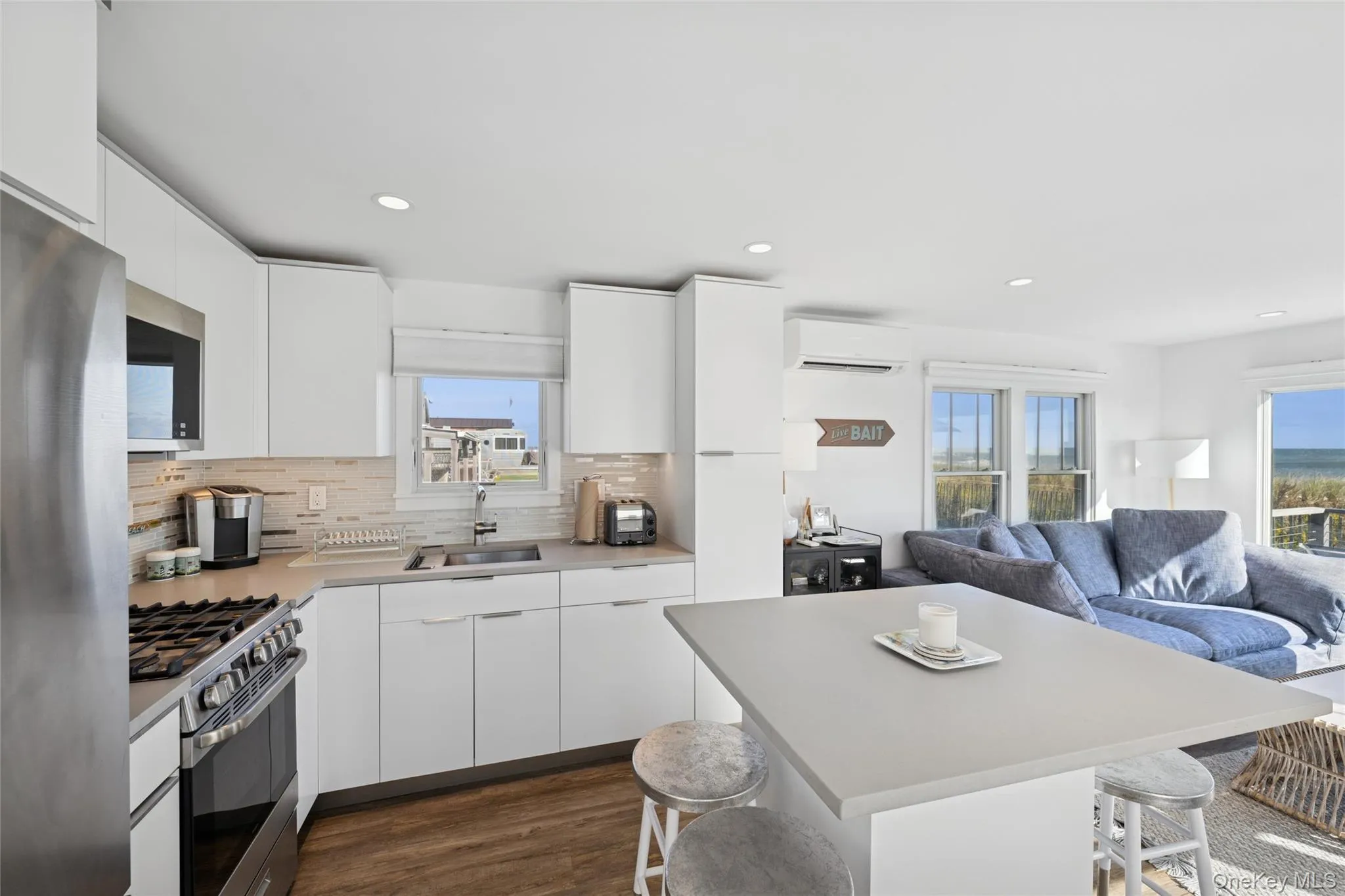 Kitchen with a breakfast bar, white cabinets, stainless steel appliances, modern cabinets, and recessed lighting Kitchen with a breakfast bar, white cabinets, stainless steel appliances, modern cabinets, and recessed lighting