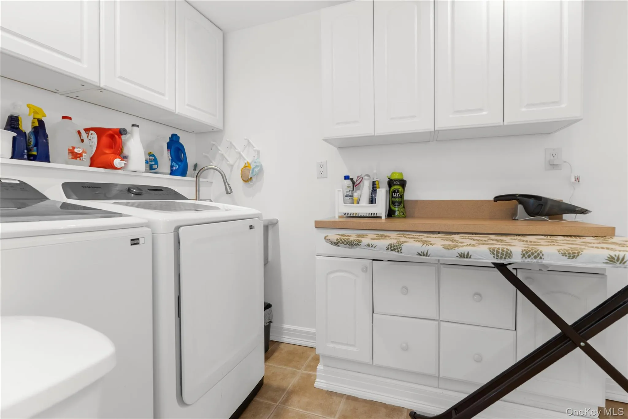 Washroom with light tile patterned flooring, separate washer and dryer, and cabinet space Washroom with light tile patterned flooring, separate washer and dryer, and cabinet space