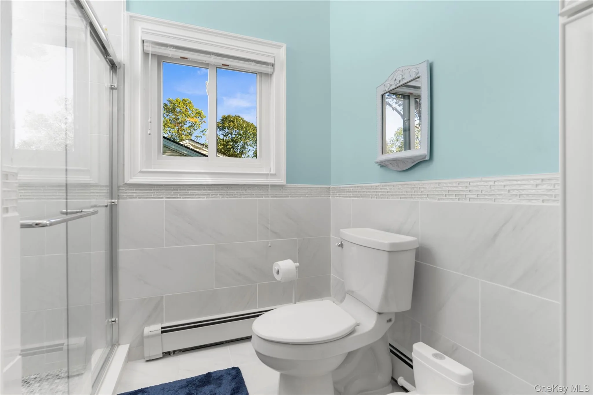 Full bathroom with double vanity, a shower with curtain, tile walls and light tile patterned floors. Full bathroom with double vanity, a shower with curtain, tile walls and light tile patterned floors.