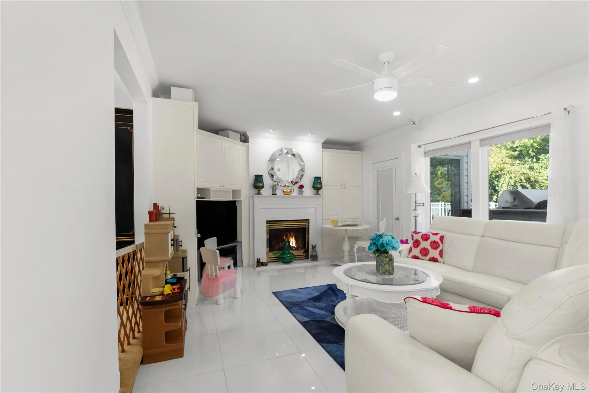 Living room featuring a warm lit fireplace, light tile patterned floors, a ceiling fan, and recessed lighting Living room featuring a warm lit fireplace, light tile patterned floors, a ceiling fan, and recessed lighting