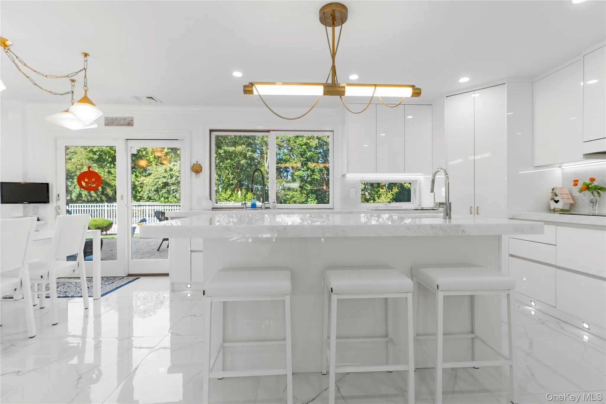 Kitchen featuring modern cabinets, a kitchen bar, white cabinetry, light stone counters, and recessed lighting Kitchen featuring modern cabinets, a kitchen bar, white cabinetry, light stone counters, and recessed lighting