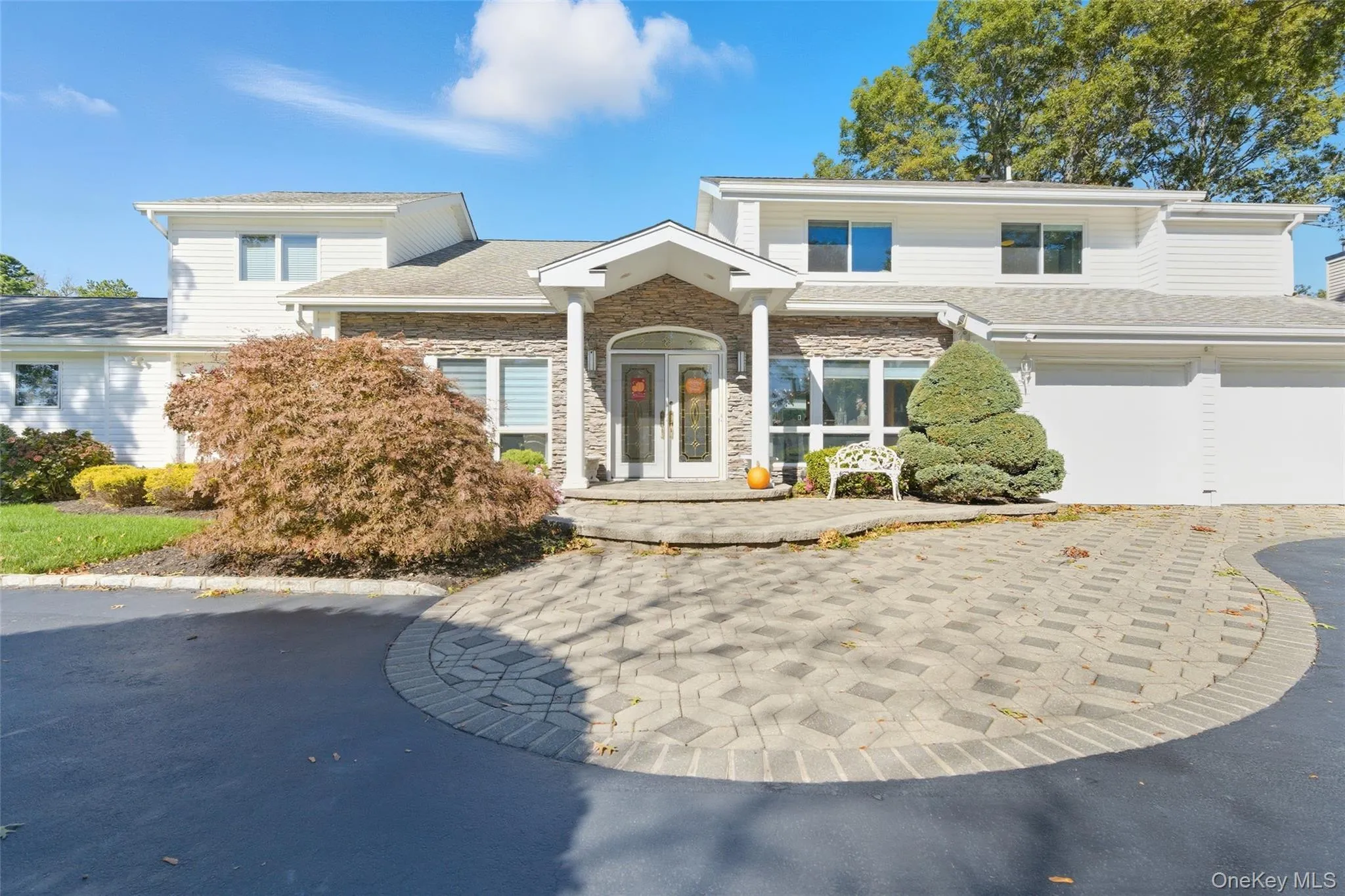 View of front of property featuring stone siding, driveway, french doors, and a garage View of front of property featuring stone siding, driveway, french doors, and a garage
