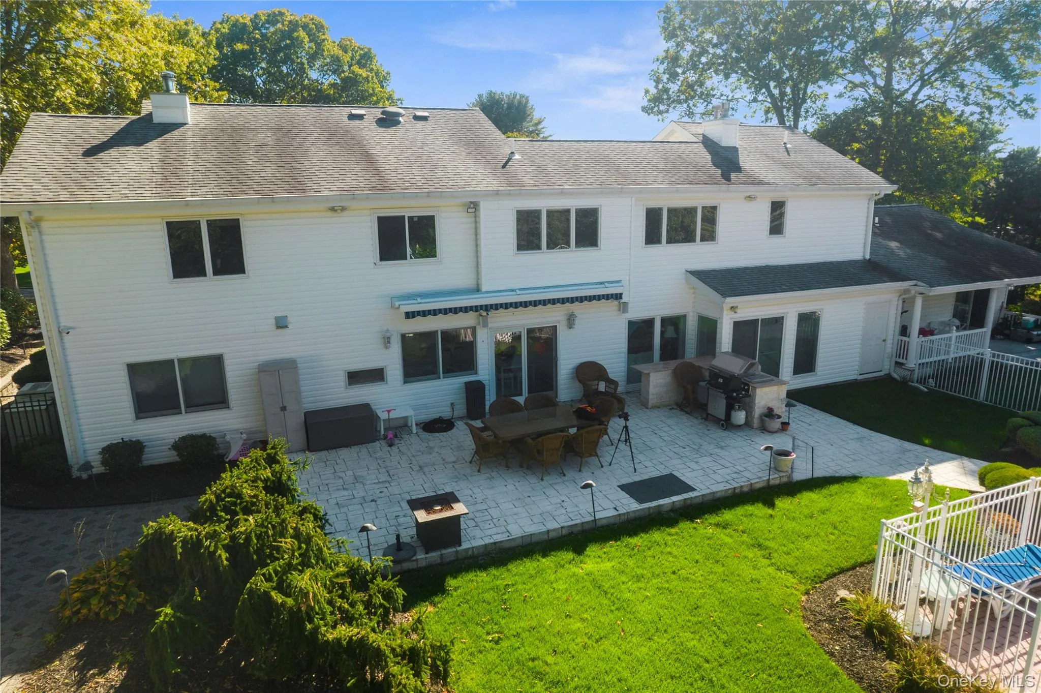 Back of property featuring a patio, a chimney, a shingled roof, and a fire pit Back of property featuring a patio, a chimney, a shingled roof, and a fire pit