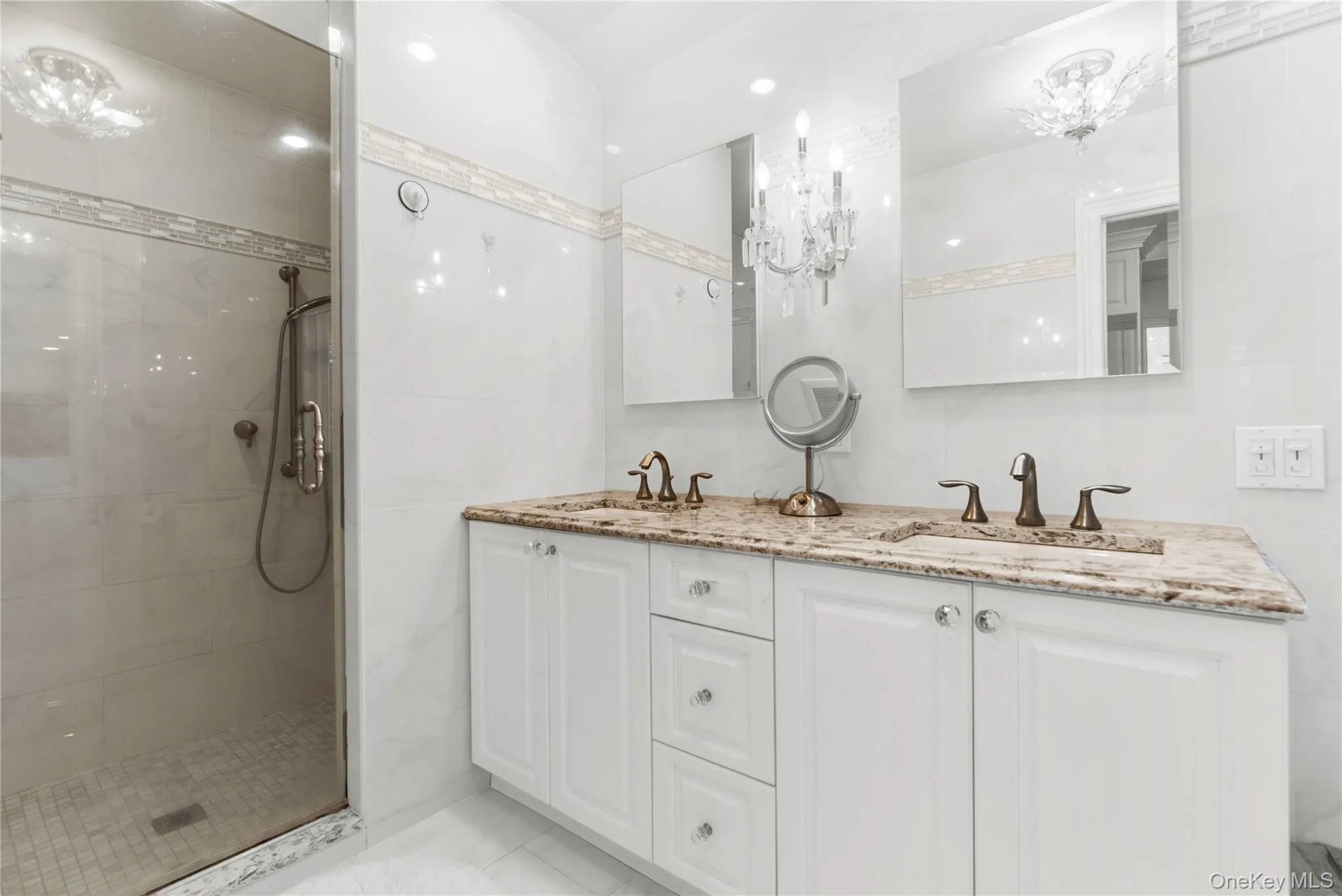 Bathroom featuring double vanity, a shower stall, and a chandelier Bathroom featuring double vanity, a shower stall, and a chandelier