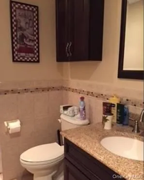 Bathroom featuring tile walls, wainscoting, and vanity Bathroom featuring tile walls, wainscoting, and vanity