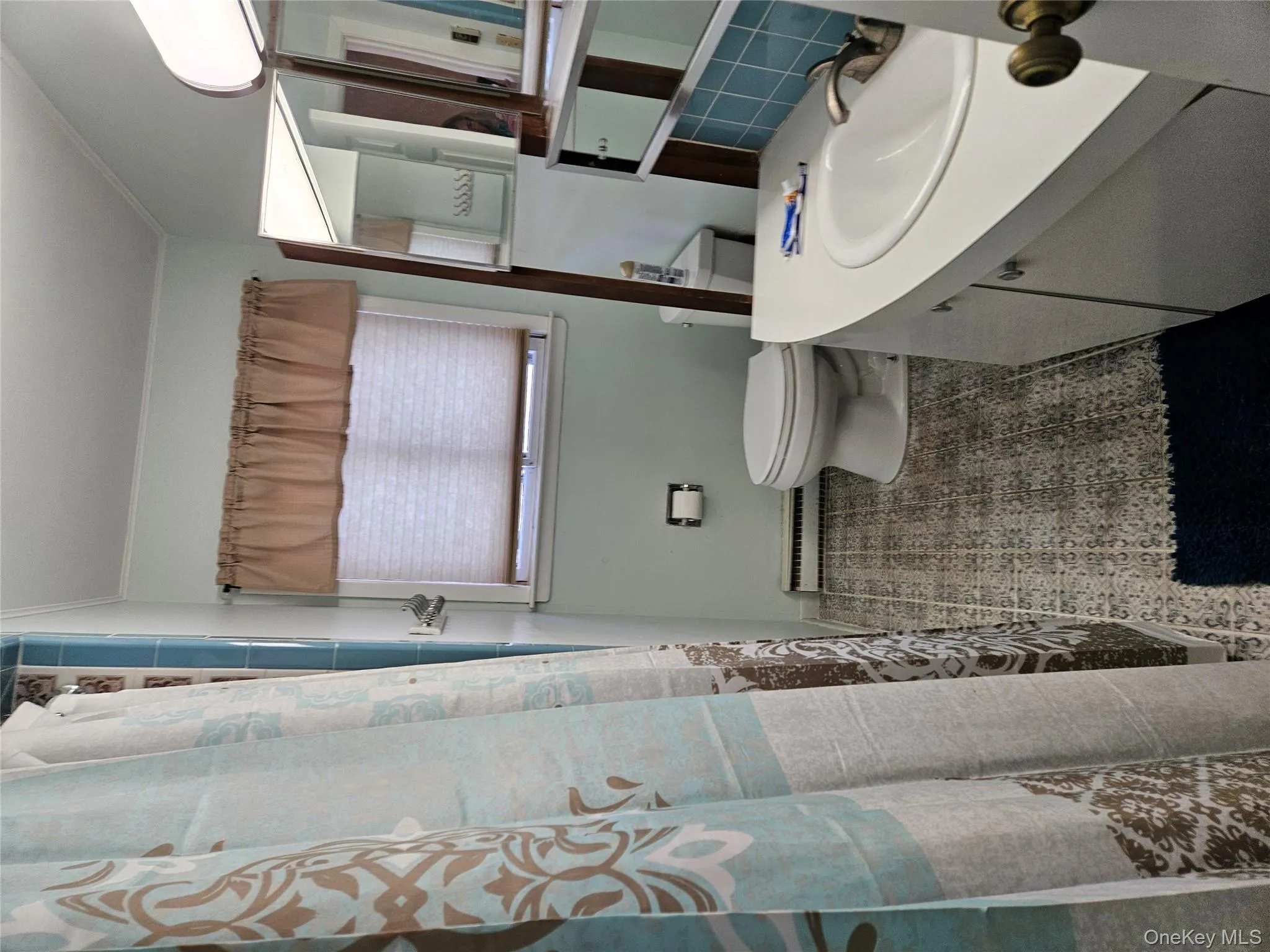 Full bathroom with vanity, a shower with shower curtain, baseboard heating, crown molding, and tasteful backsplash Full bathroom with vanity, a shower with shower curtain, baseboard heating, crown molding, and tasteful backsplash