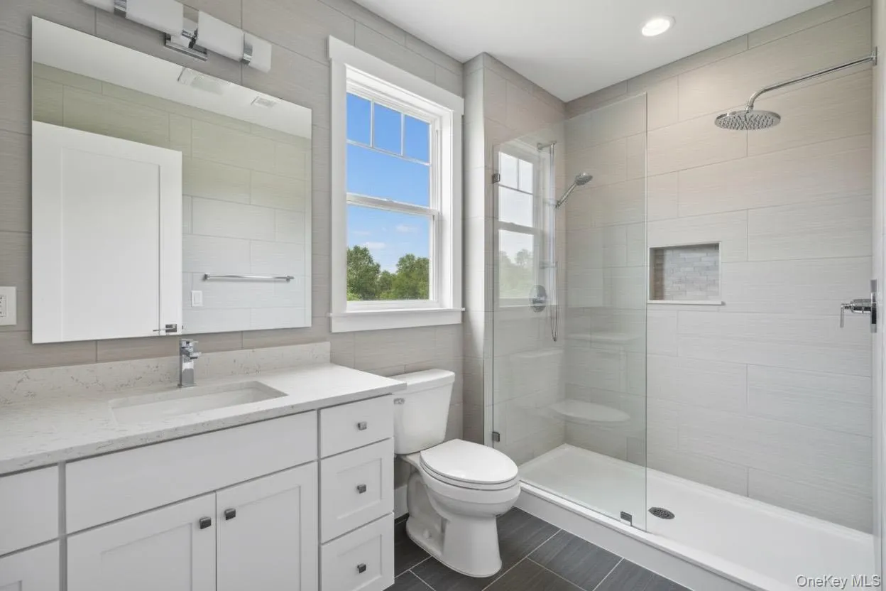 Bathroom featuring tile walls, vanity, and a shower stall Bathroom featuring tile walls, vanity, and a shower stall