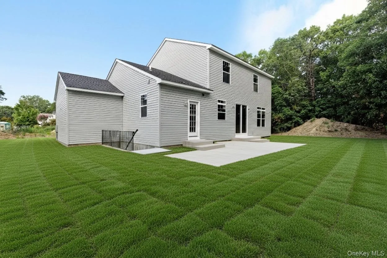 Rear view of house with a lawn, a patio, a shingled roof, and entry steps Rear view of house with a lawn, a patio, a shingled roof, and entry steps