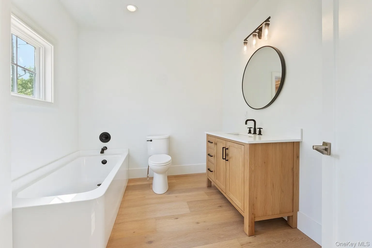 Full bathroom featuring a bath, light wood finished floors, vanity, and recessed lighting Full bathroom featuring a bath, light wood finished floors, vanity, and recessed lighting