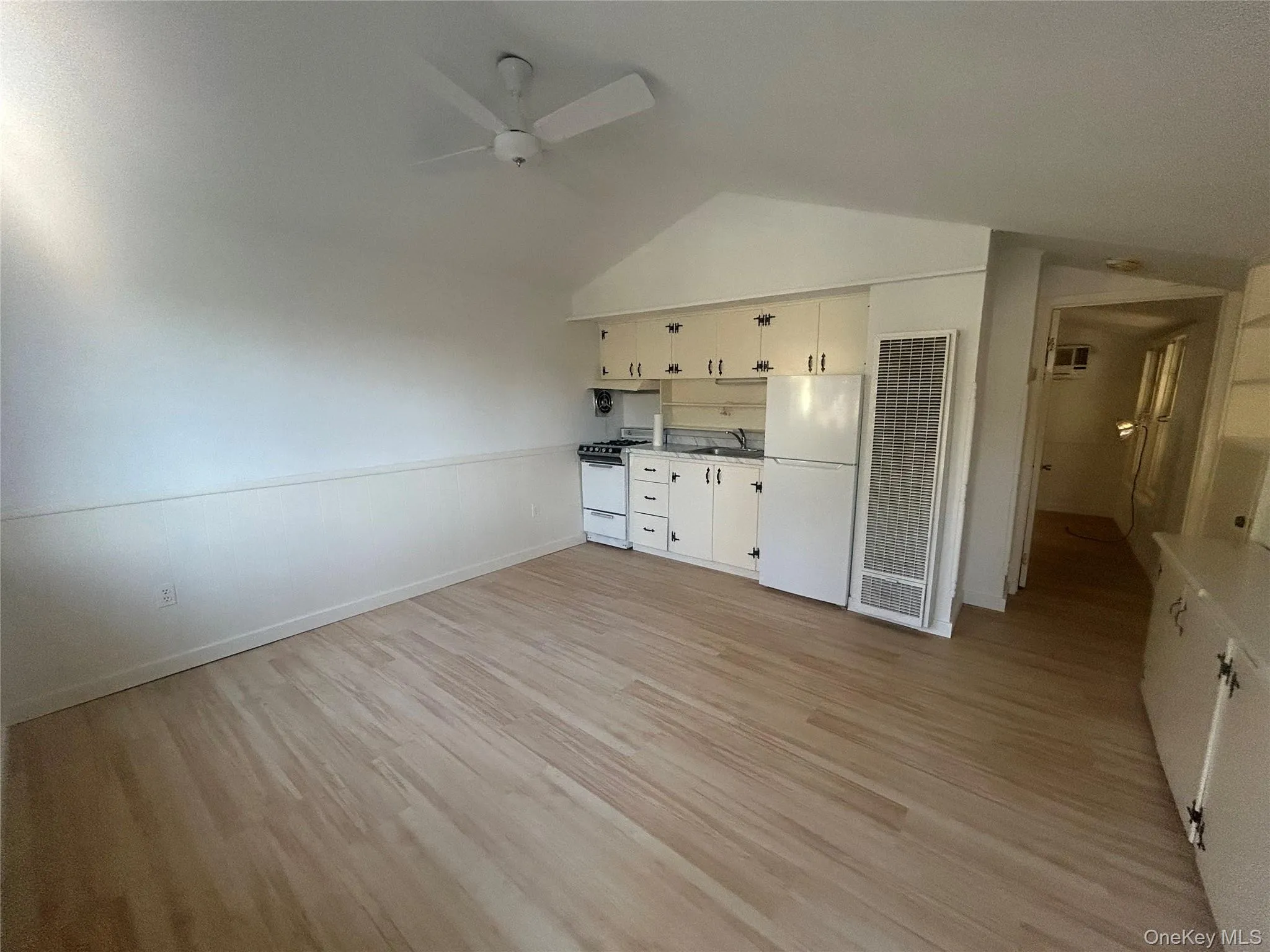Unfurnished living room featuring light wood-style floors, a heating unit, lofted ceiling, and a ceiling fan Unfurnished living room featuring light wood-style floors, a heating unit, lofted ceiling, and a ceiling fan