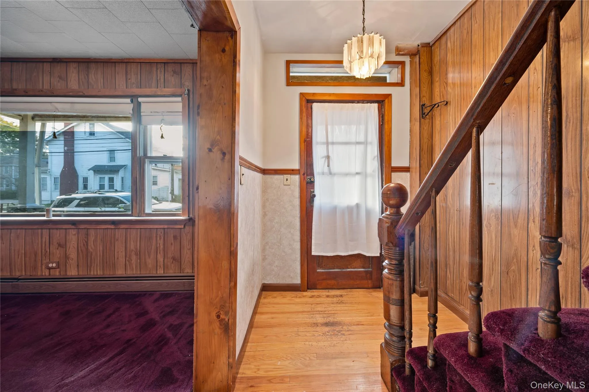Entrance foyer with wood walls, light wood-style floors, stairs, a baseboard heating unit, and wainscoting Entrance foyer with wood walls, light wood-style floors, stairs, a baseboard heating unit, and wainscoting