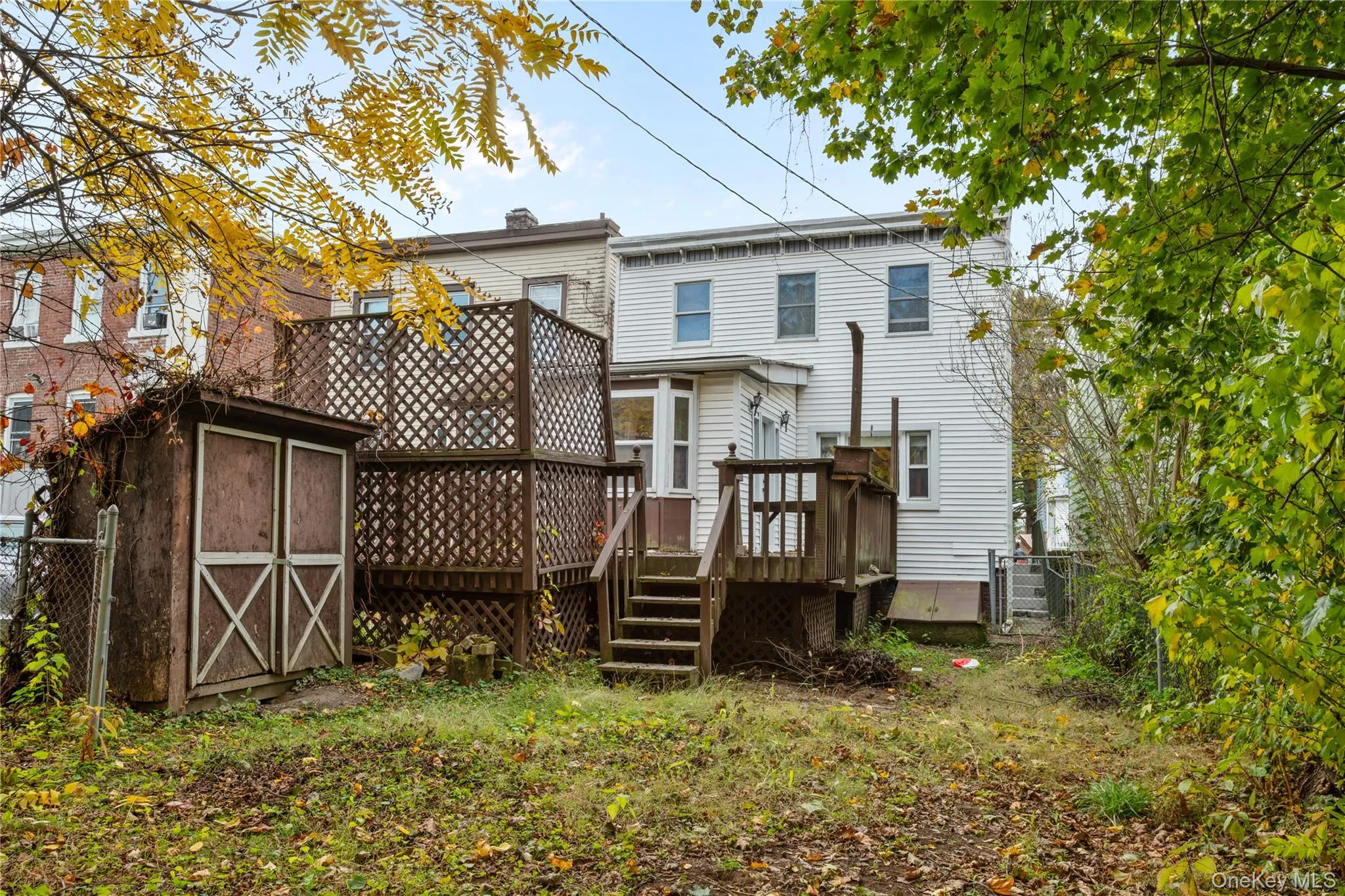 Rear view of property featuring a storage unit and a wooden deck Rear view of property featuring a storage unit and a wooden deck