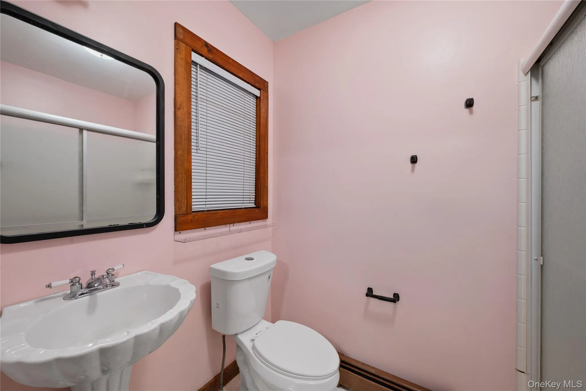 Full bath featuring a shower with door and a baseboard heating unit Full bath featuring a shower with door and a baseboard heating unit